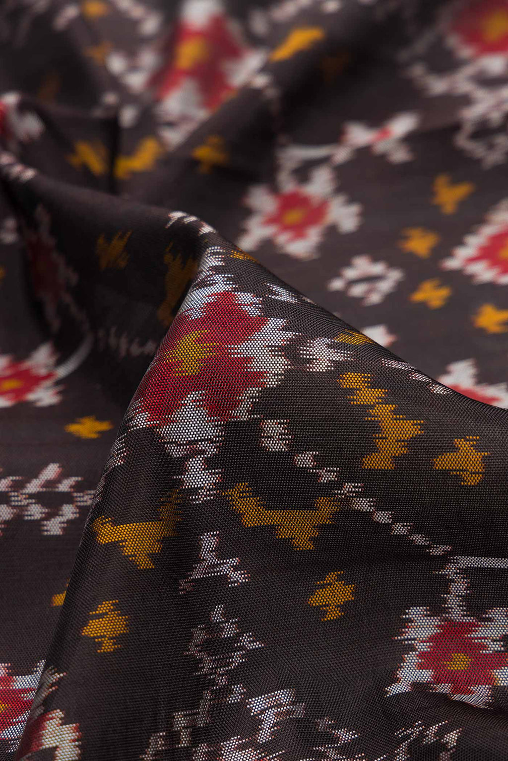 Close up of Black Dual Tone Rajkot Patola Silk Saree with Ikat Print on the body and Zari Border.  displaying folds