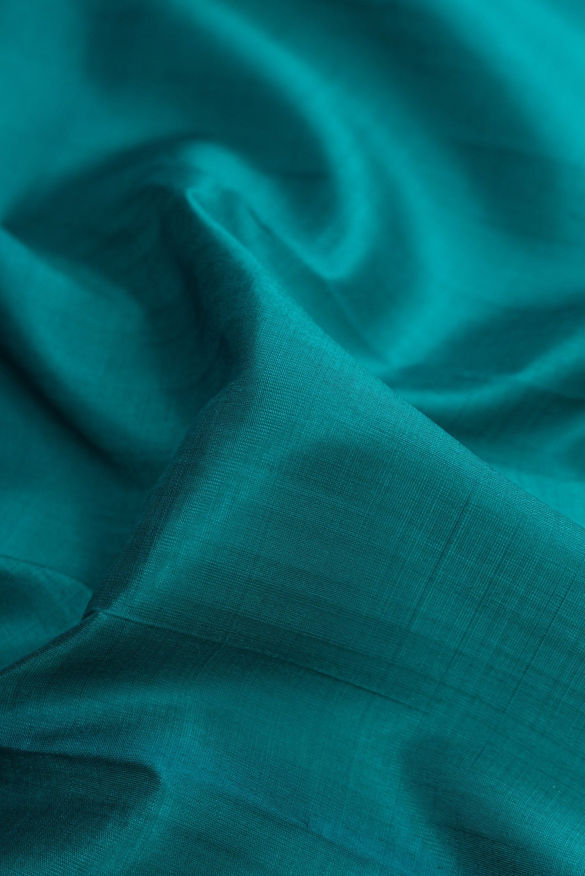 Close up of Peacock Blue Dual Tone Kanchipuram Silk Saree with Plain Body and Zari Border.  displaying folds