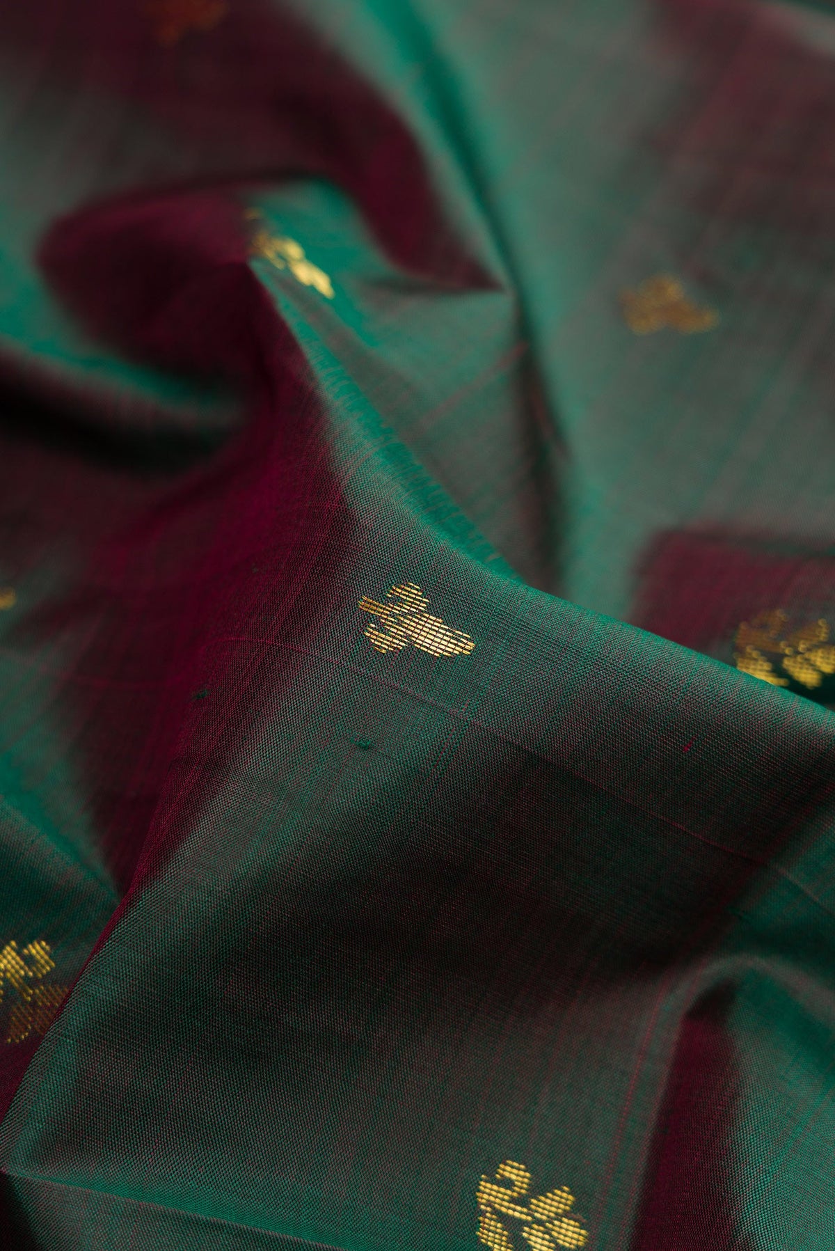 Close up of Bottle Green Dual Tone Kanchipuram Silk Saree with Zari Butta on the body and Zari Border.  displaying folds