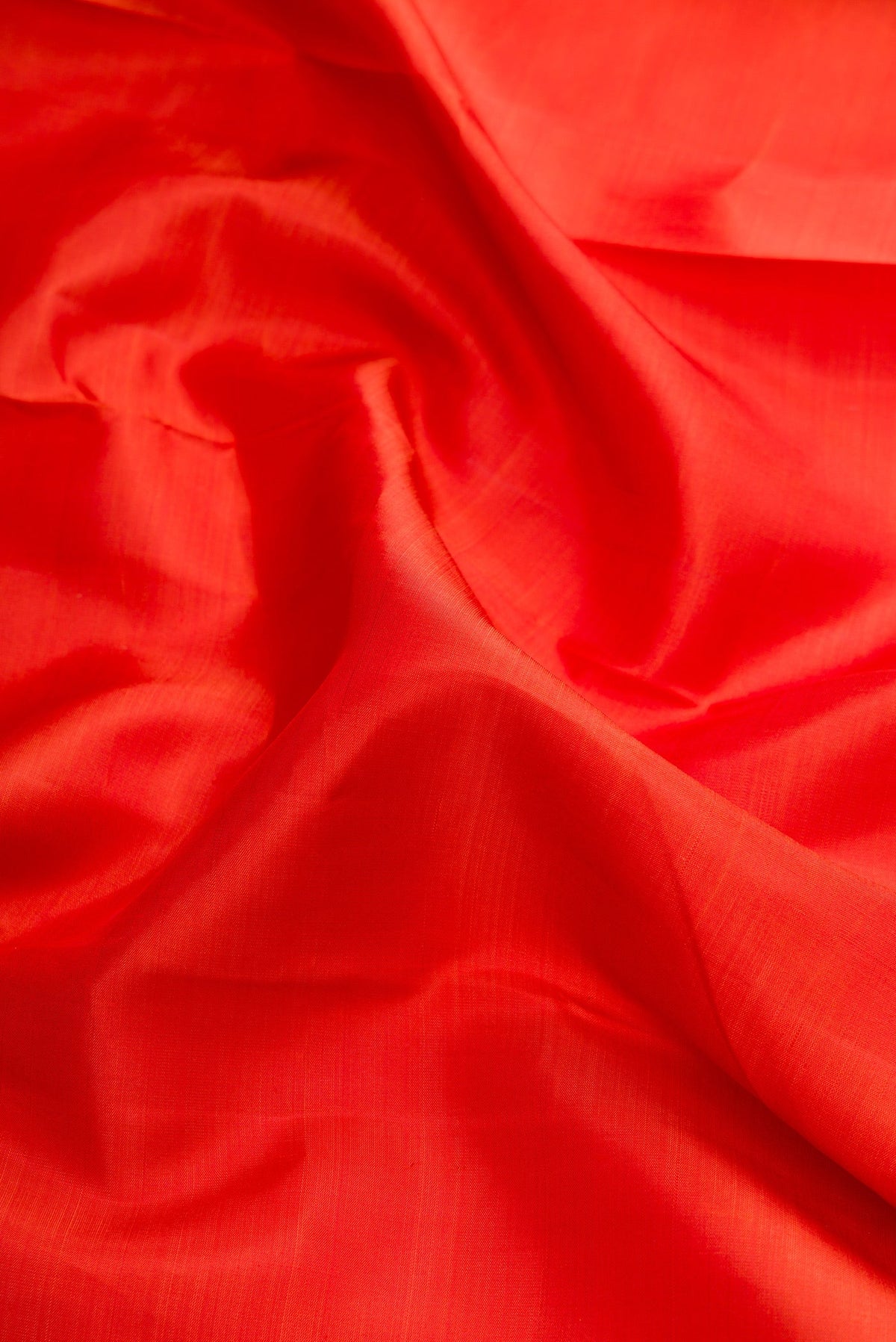 Close up of Brick Orange Dual Tone Kanjivaram Silk Saree with Plain Body and Zari Border.  displaying folds