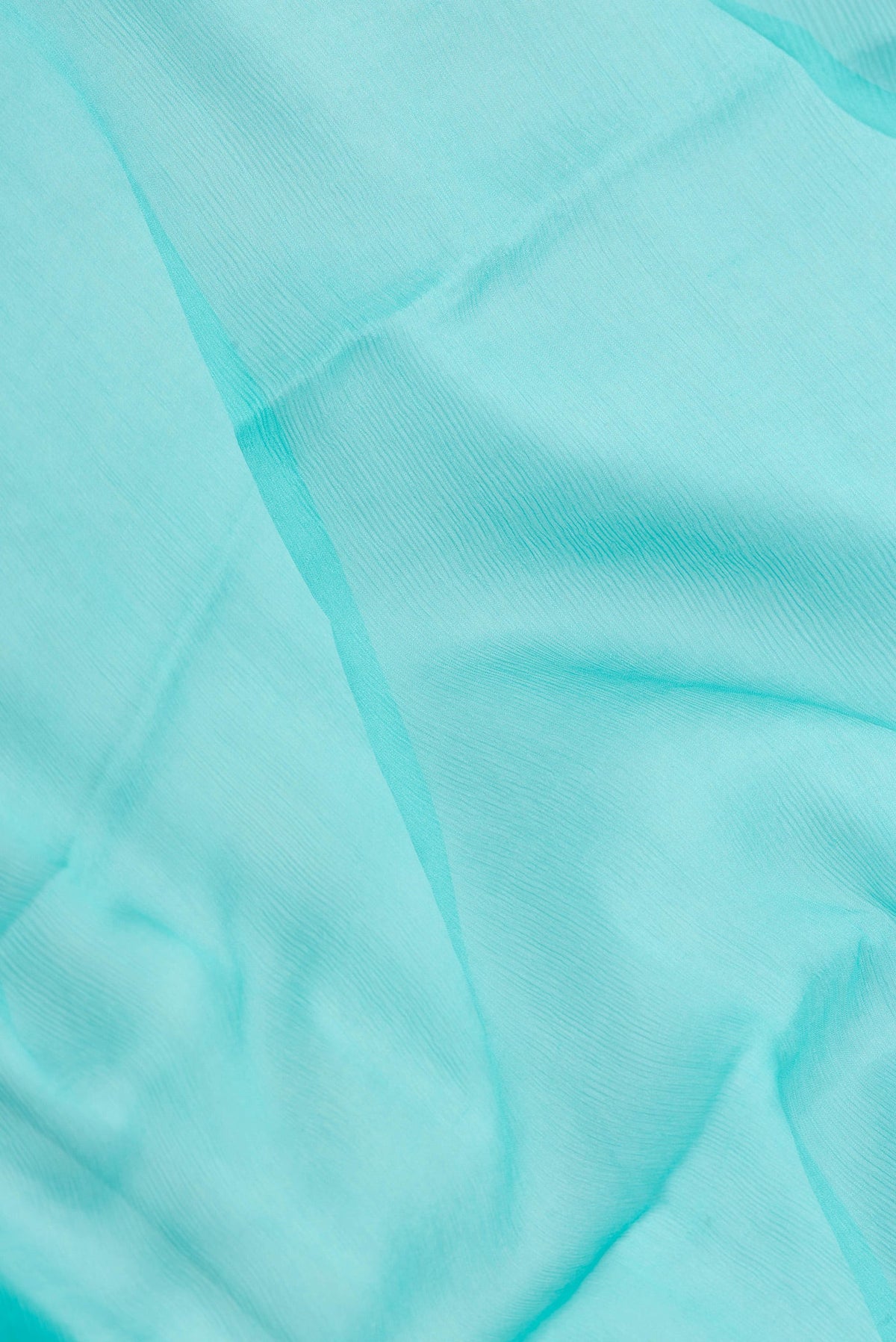 Close up of Sky Blue Mysore Chiffon Saree with Plain Body and Zari Border.  displaying folds