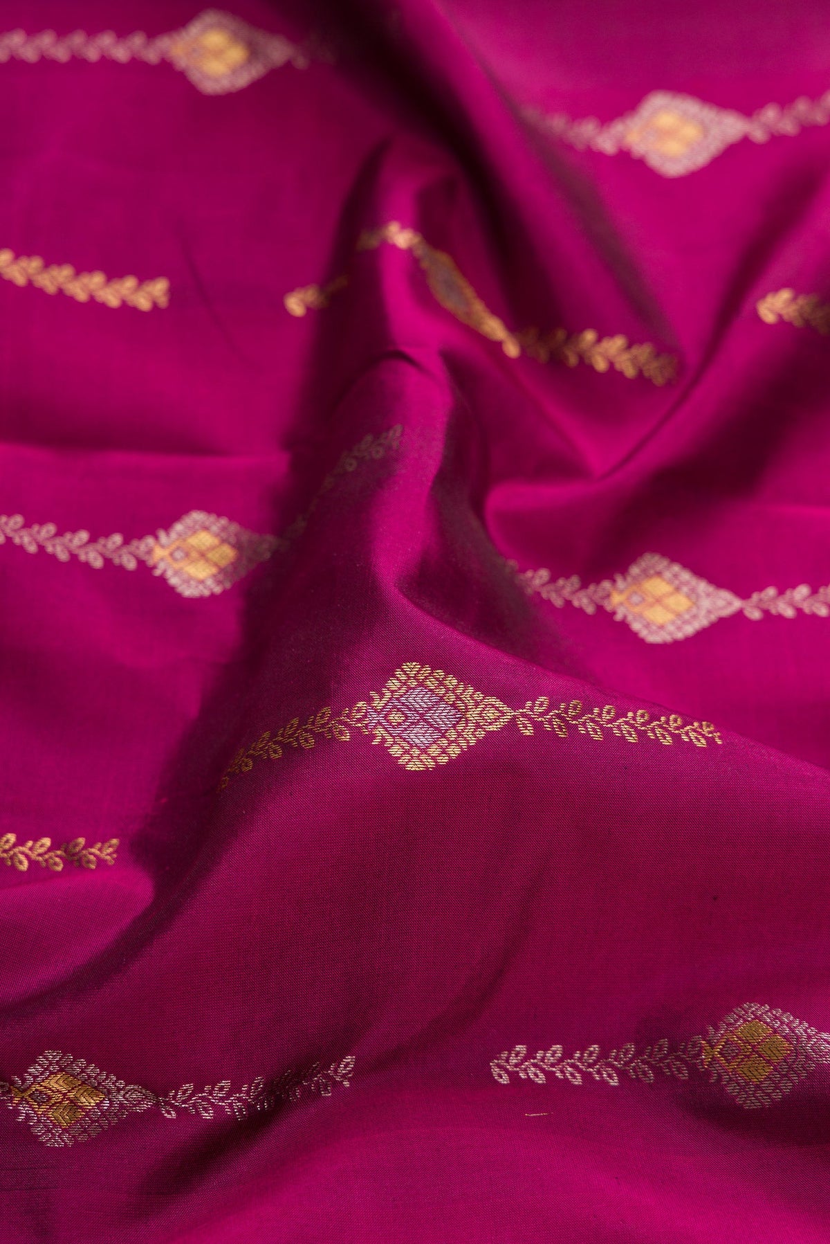 Close up of Magenta Dual Tone Kanchipuram Silk Saree with Zari Butta on the body and Zari Border.  displaying folds
