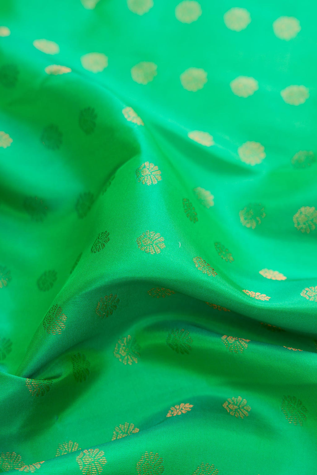 Close up of Green Dual Tone Kanchipuram Silk Saree with Zari Butta on the body and Zari Border displaying folds