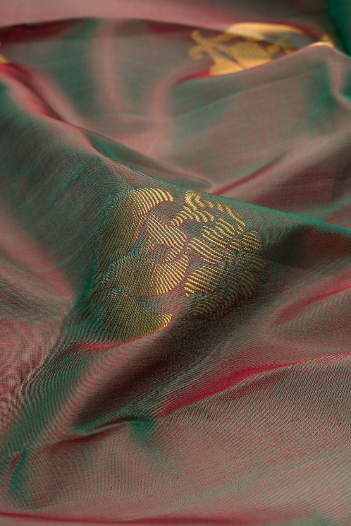 Close up of Green Dual Tone Soft Silk Saree with Zari Butta on the body and Zari Border.  displaying folds