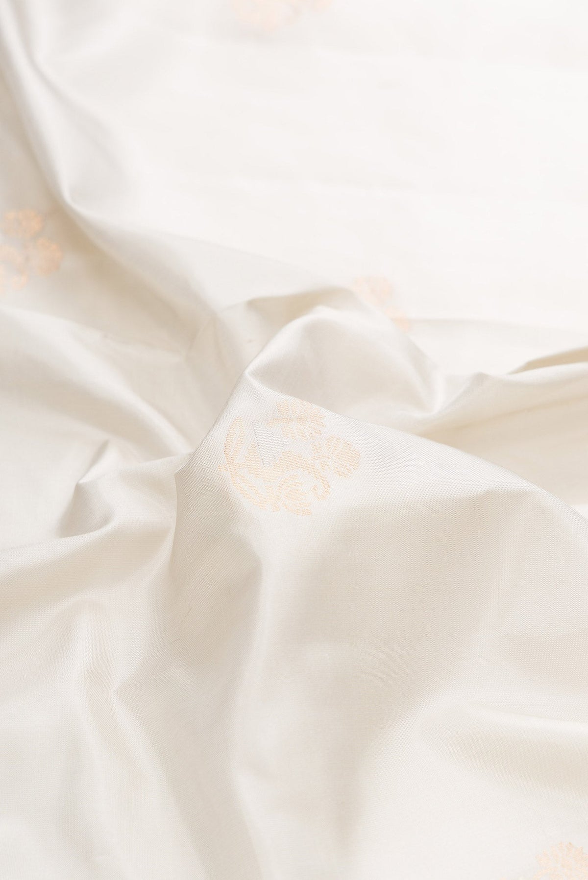 Close up of Off White Dual Tone Soft Silk Saree with Zari Butta on the body and Zari Border displaying folds