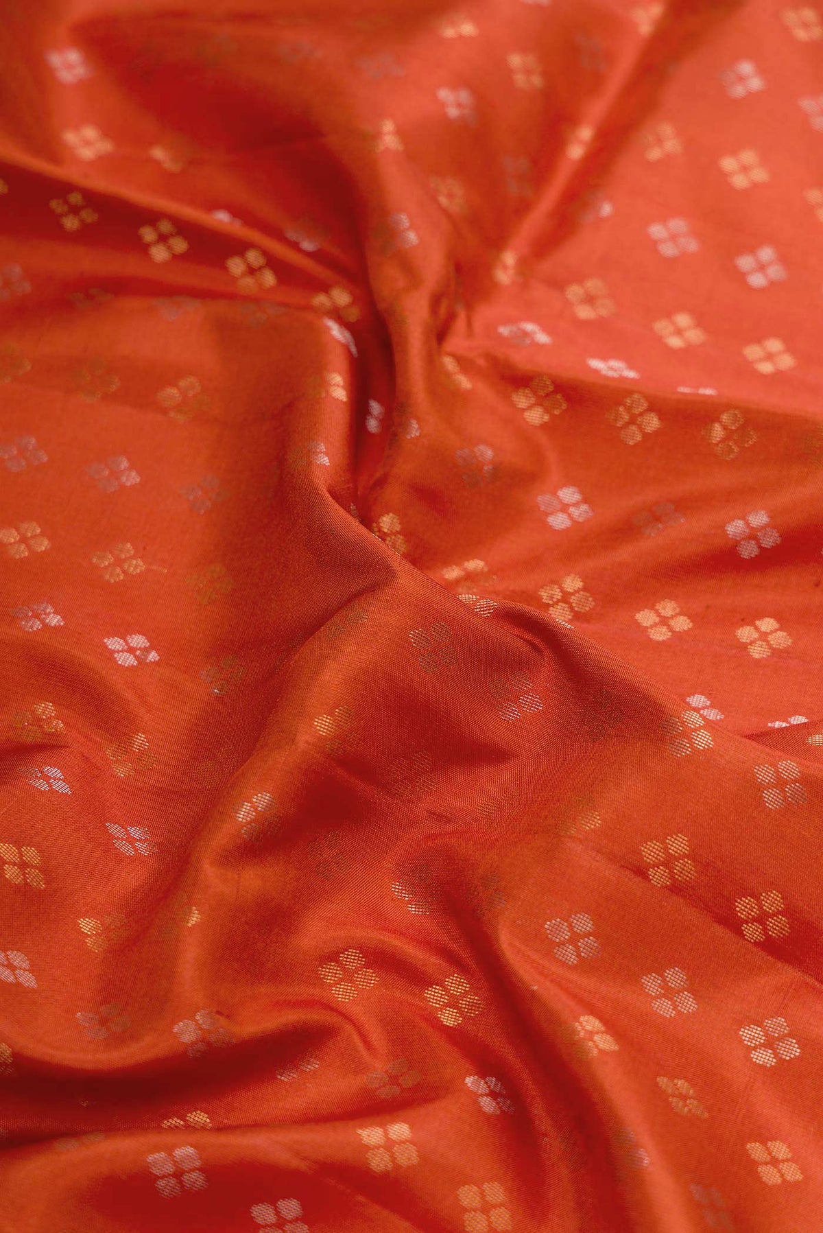 Close up of Orange Dual Tone Soft Silk Saree with Zari Butta on the body and Zari Border displaying folds
