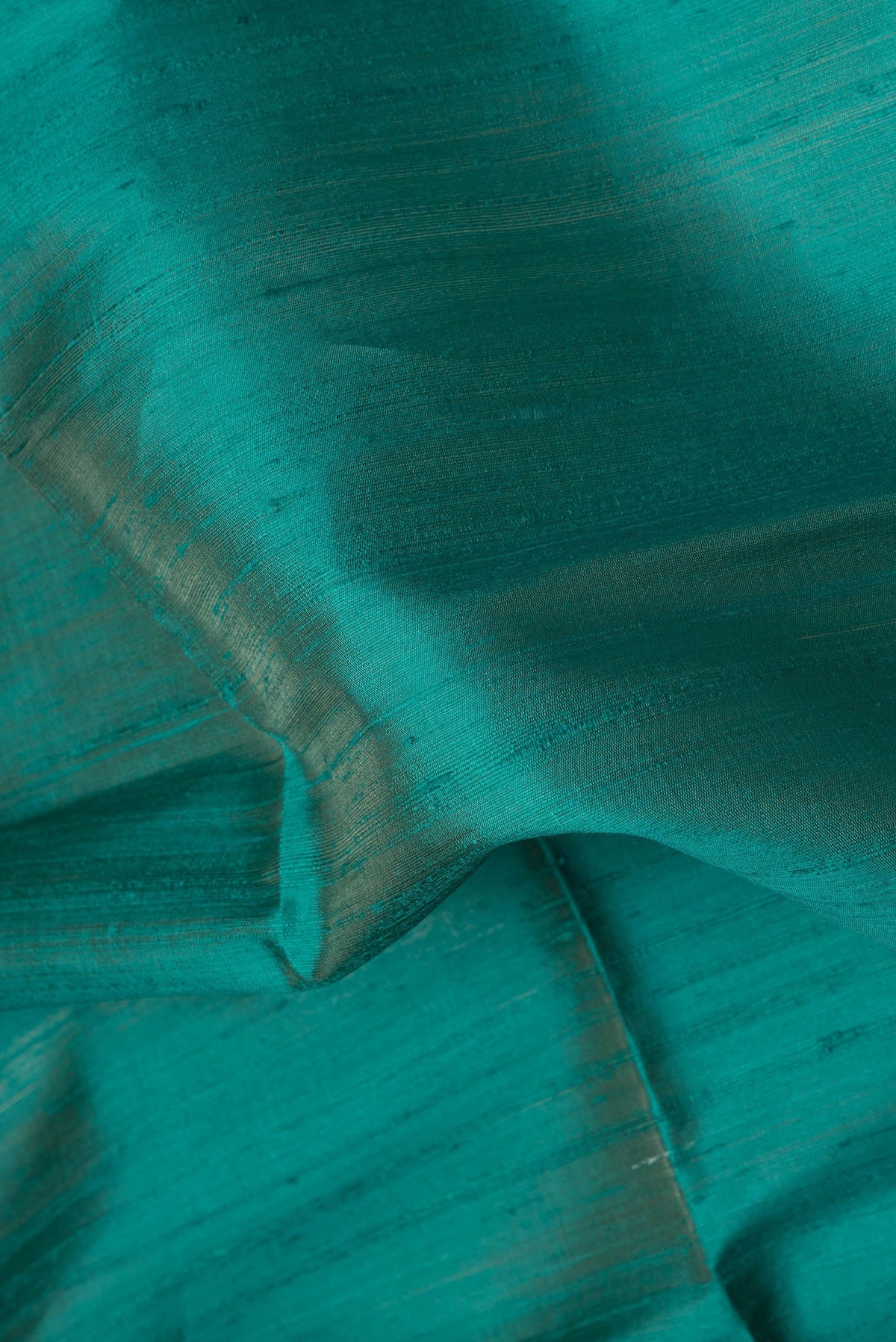 Close up of Peacock Blue Dual Tone Raw Silk Saree with Plain Body and Thin Zari Line.  displaying folds