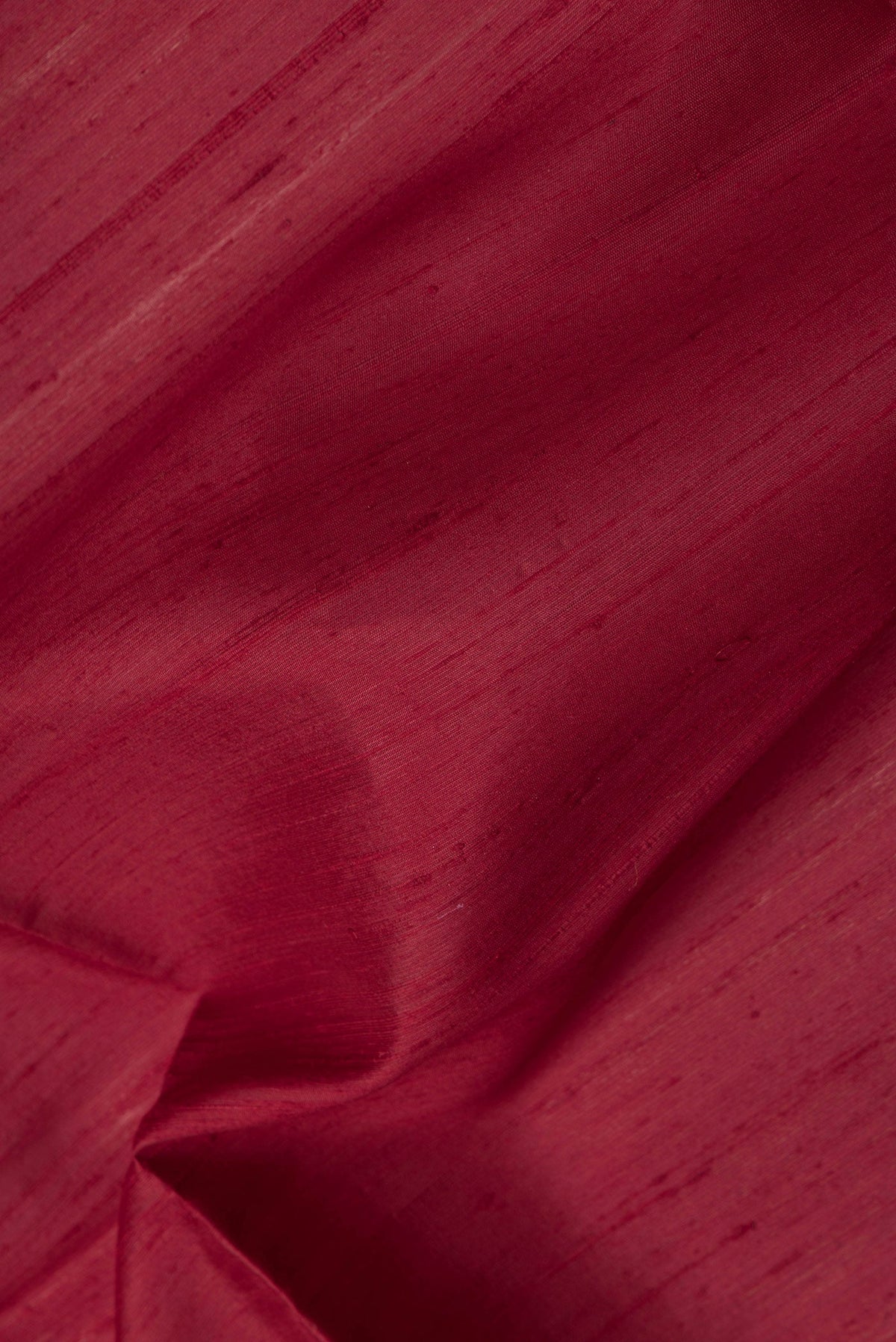 Close up of Maroon Dual Tone Raw Silk Saree with Plain Body and Thin Zari Line.  displaying folds