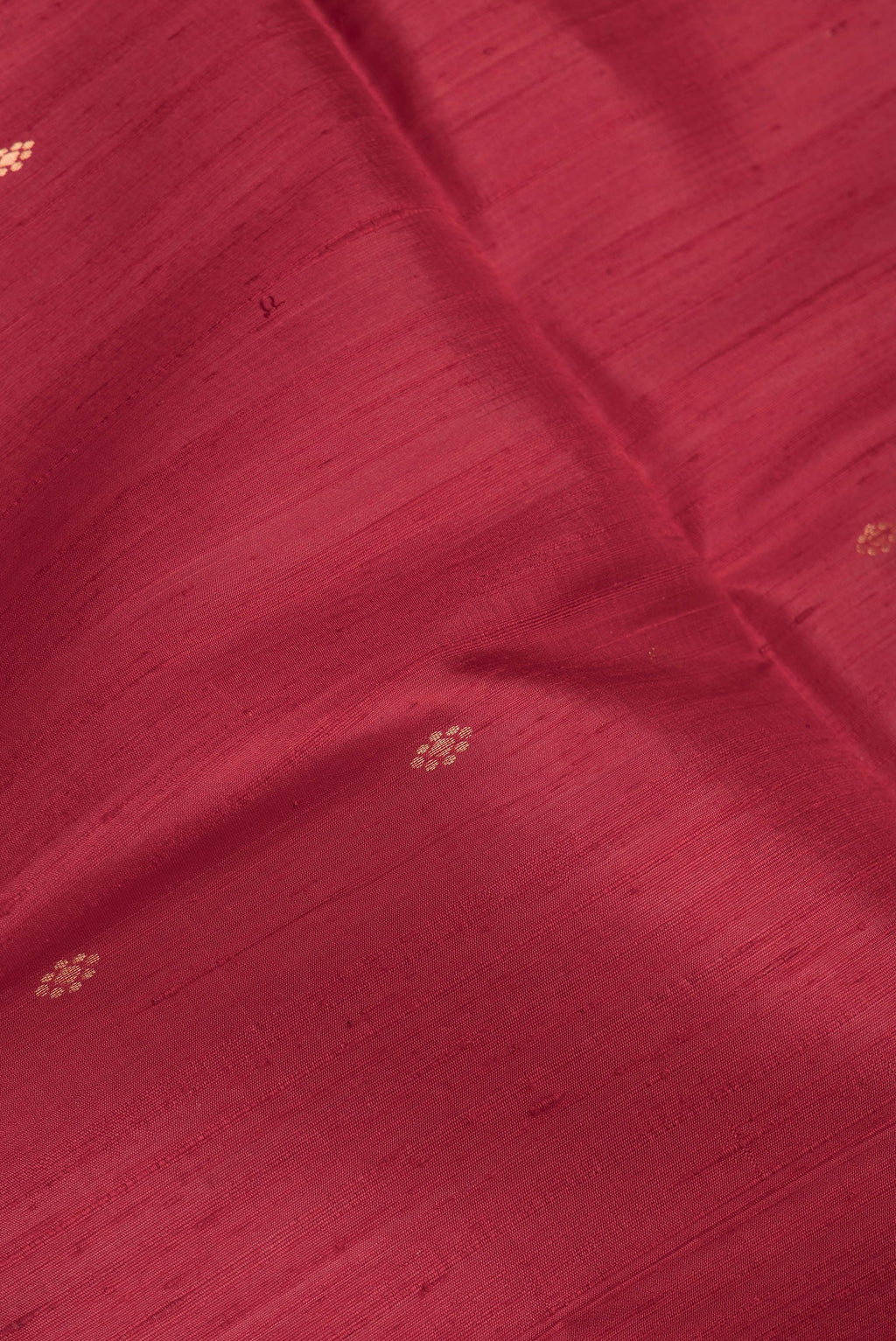 Close up of Maroon Dual Tone Raw Silk Saree with Zari Butta on the body and Fancy Border.  displaying folds
