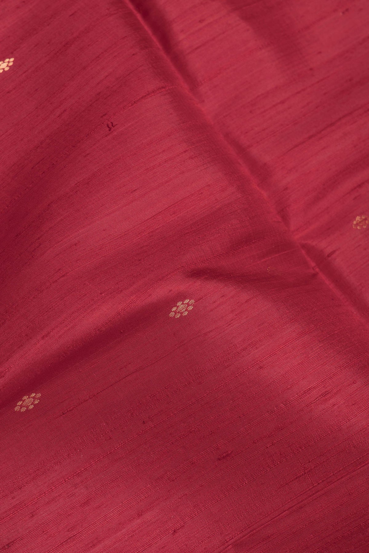 Close up of Maroon Dual Tone Raw Silk Saree with Zari Butta on the body and Fancy Border.  displaying folds
