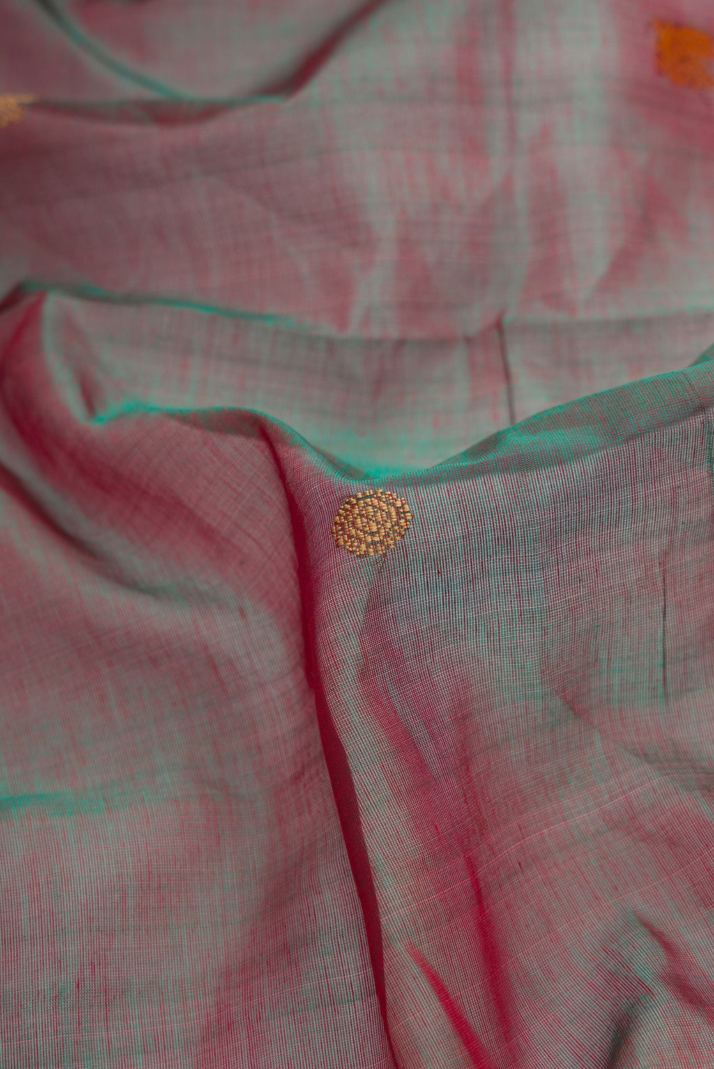 Close up of Red Dual Tone Silk Cotton Saree with Thread Butta on the body and Zari Border.  displaying folds