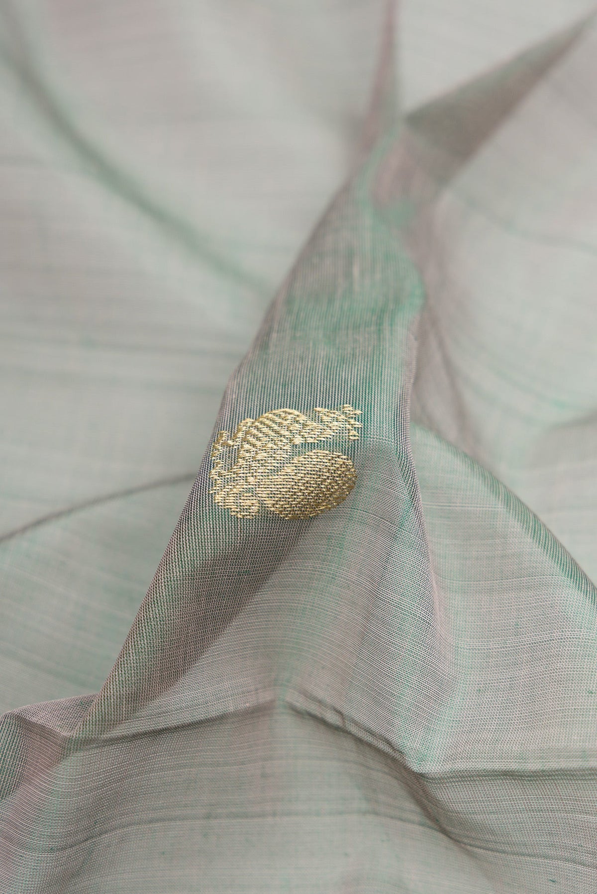 Close up of Grey with Green Color Silk Cotton Saree with Zari Butta on the body and Zari Border.  displaying folds