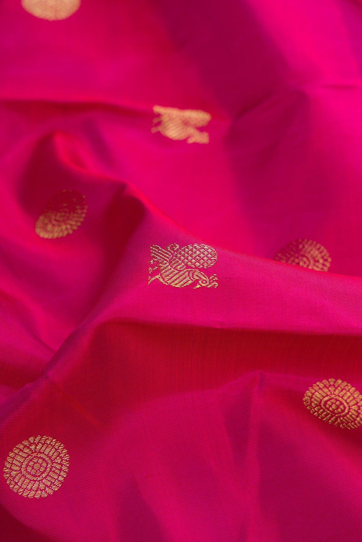 Close up of Pure Silk Pure Zari Magenta Dual Tone Kanchipuram Saree with Zari Butta on the body and Zari Border.  displaying folds