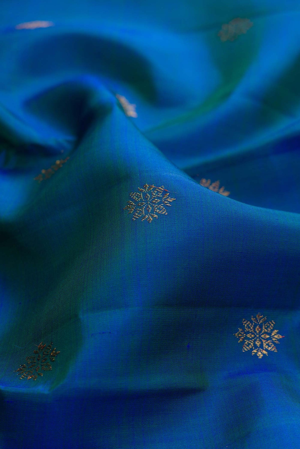 Close up of Pure Silk Pure Zari Peacock Blue Dual Tone Kanchipuram Saree with Zari Butta on the body and Zari Border displaying folds