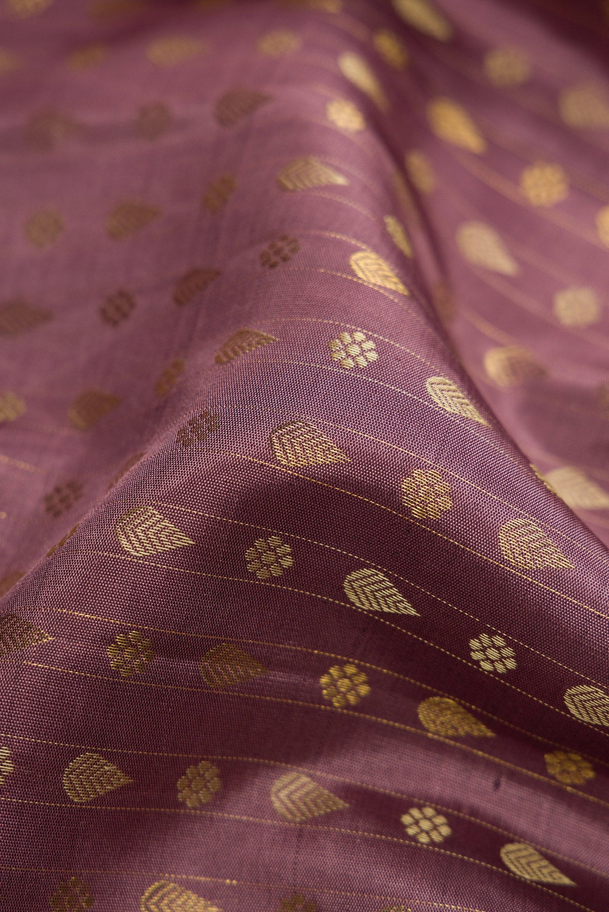 Close up of Pure Silk Pure Zari Brown Dual Tone Kanchipuram Saree with Zari And Thread Butta on the body and Zari Border.  displaying folds