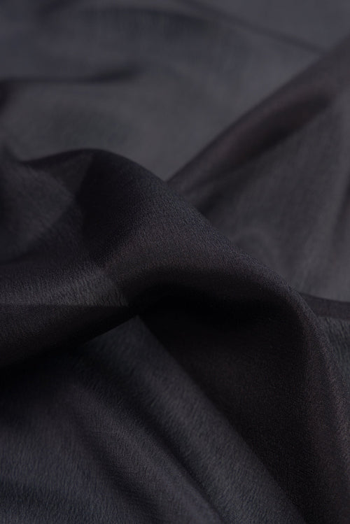 Close up of Black Mysore Crepe Saree with Plain Body and Zari Border.  displaying folds
