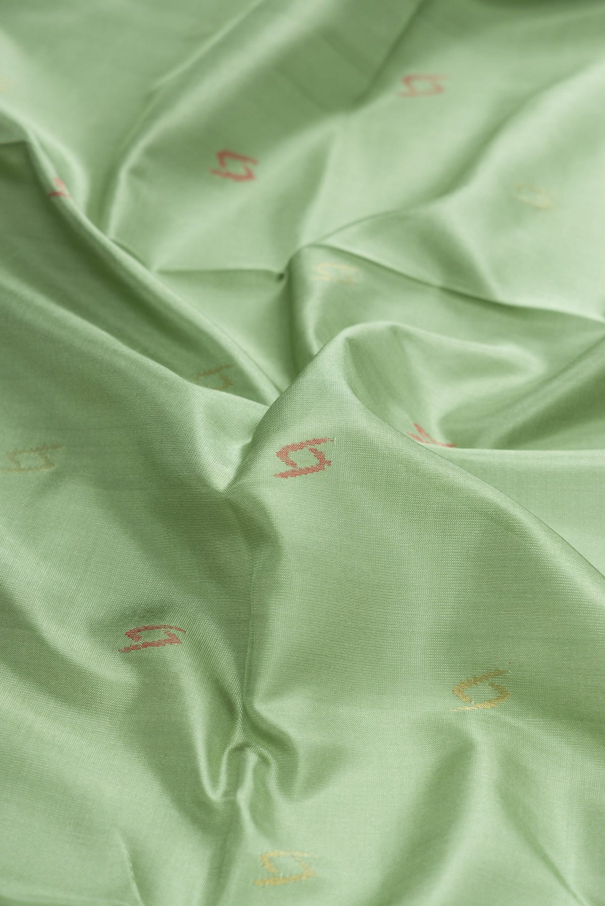 Close up of Pista Green Dual Tone Uppada Silk Saree with Zari And Thread Butta on the body and Zari Border.  displaying folds