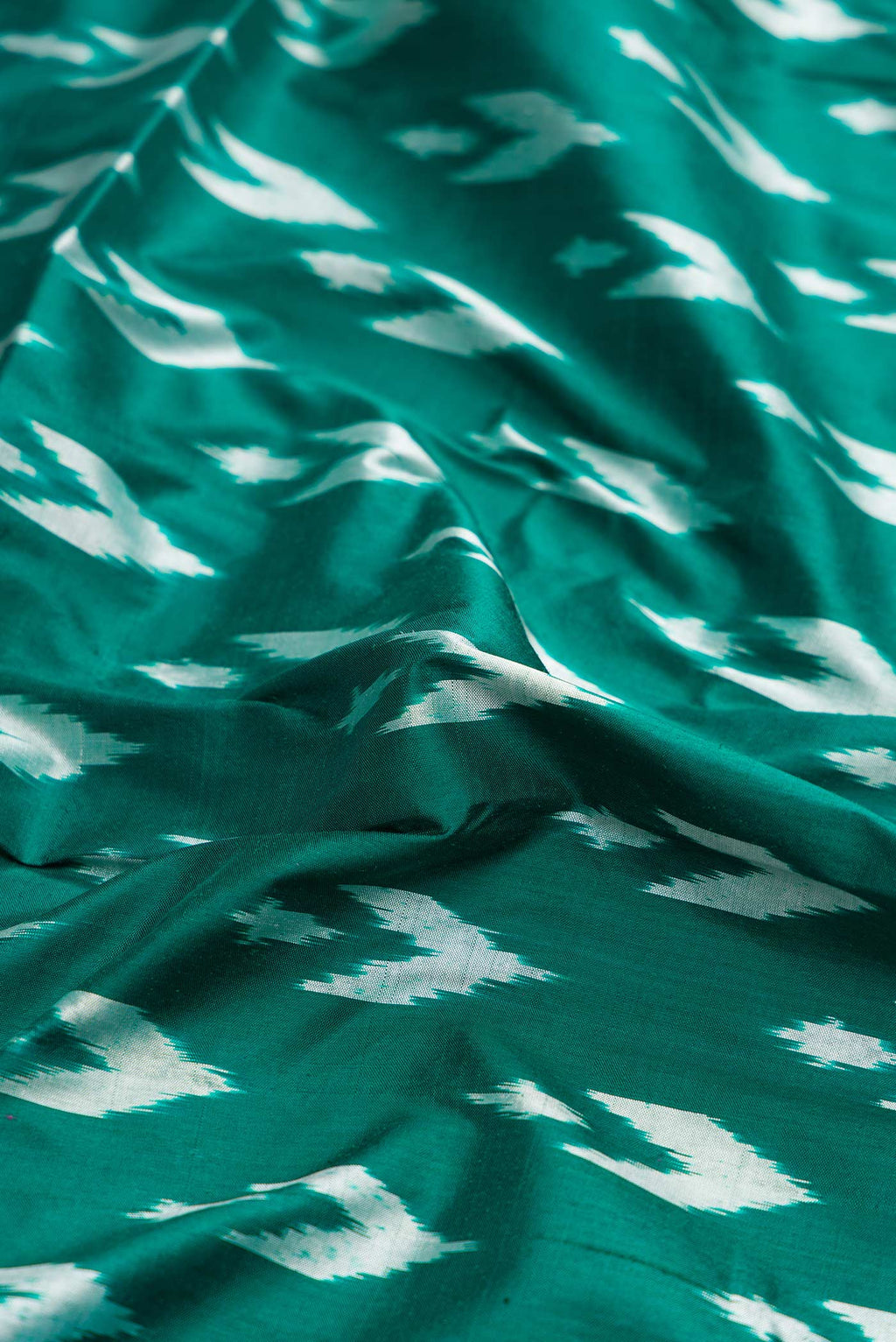 Close up of Green Dual Tone Double Ikat Saree with Ikat Print on the body and Ikat Border.  displaying folds