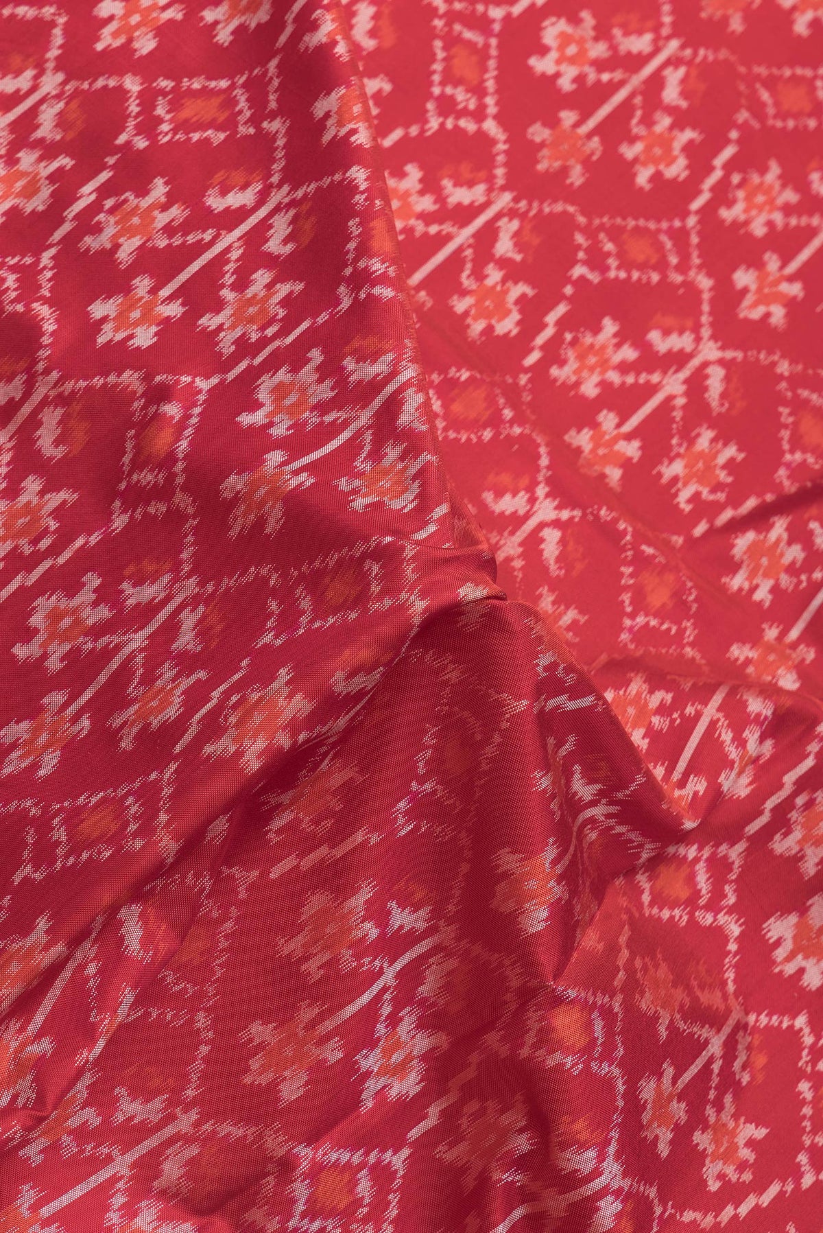 Close up of Red Dual Tone Double Ikat Saree with Ikat Print on the body and Plain Border.  displaying folds
