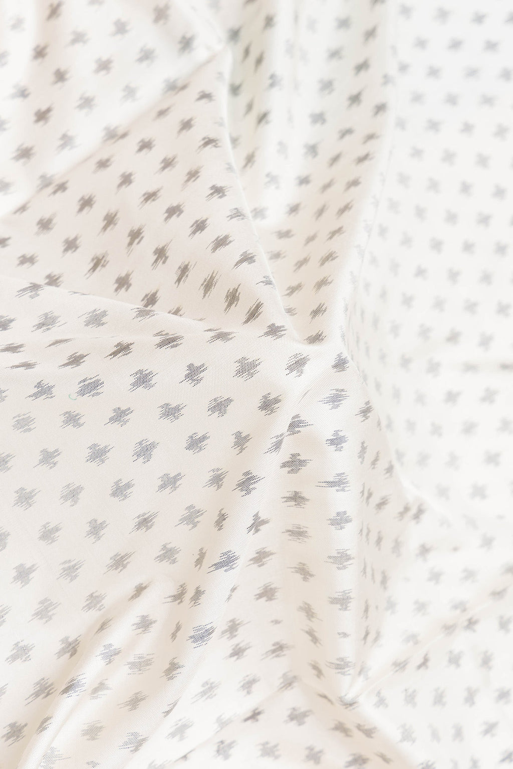 Close up of Off White Dual Tone Double Ikat Saree with Ikat Print on the body and Plain Border.  displaying folds