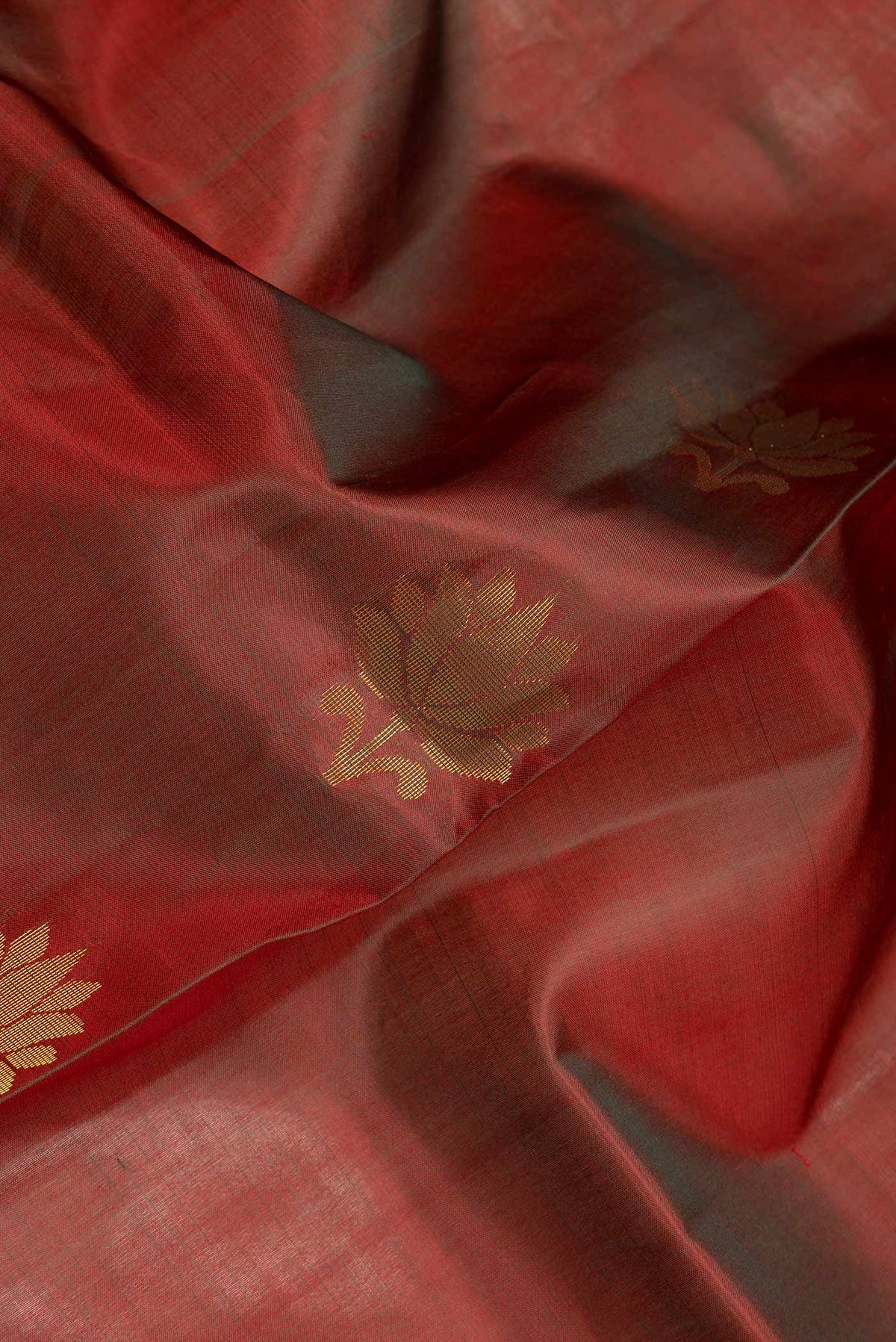 Close up of Maroon Dual Tone Soft Silk Saree with Zari Butta on the body and Zari Border.  displaying folds