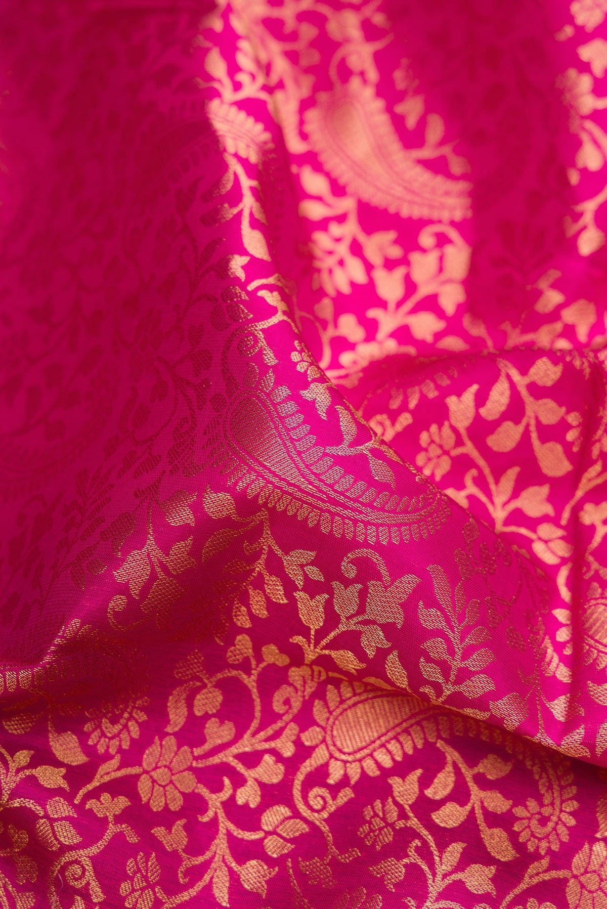 Close up of Dark Pink Kanchipuram Silk Saree with Zari Brocade on the body and Zari Border.  displaying folds