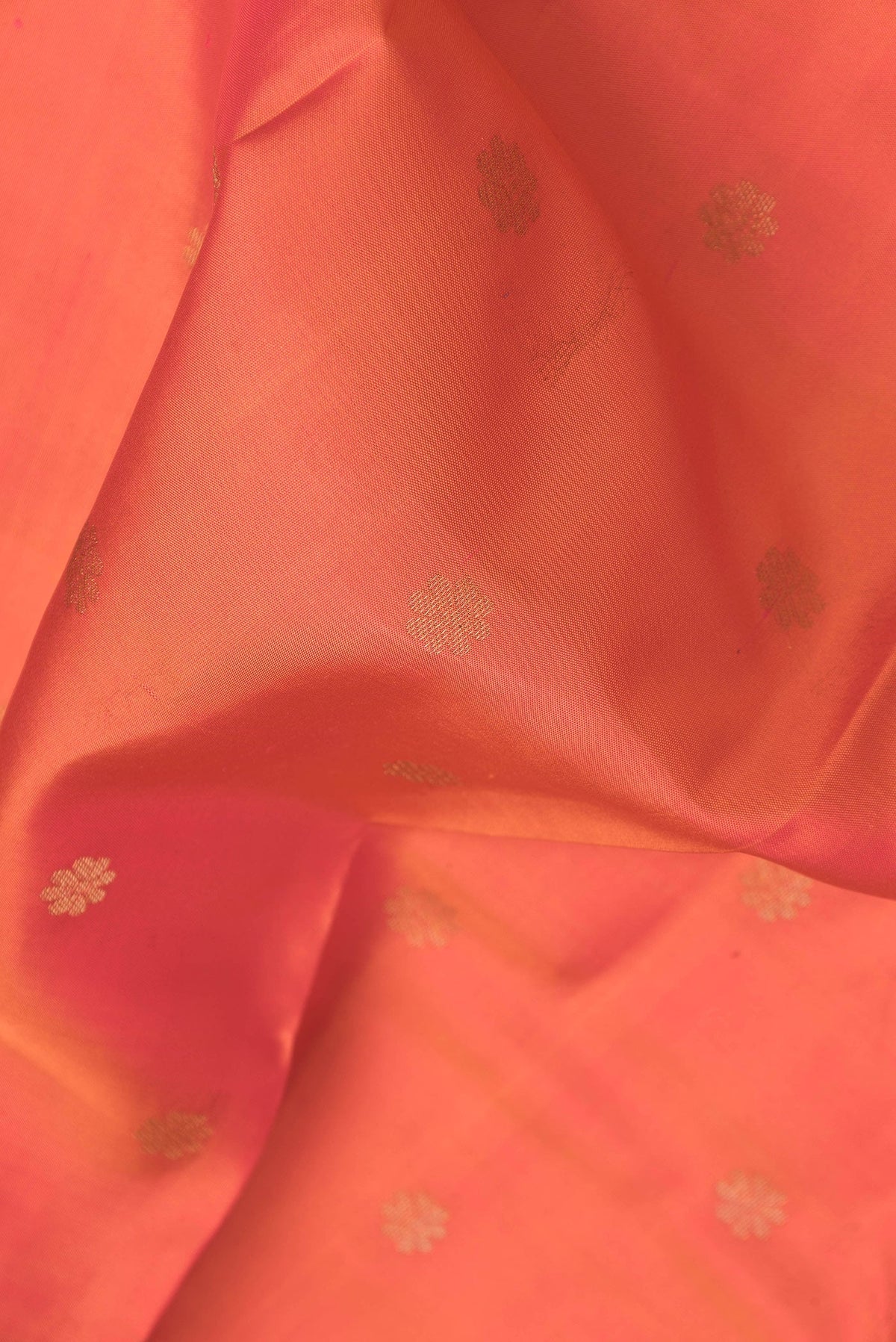 Close up of Orange Dual Tone Kanjivaram Silk Saree with Zari Butta on the body and Zari Border.  displaying folds
