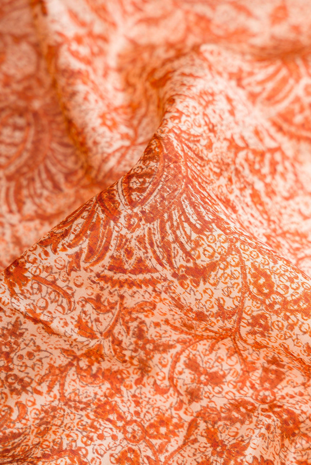 Close up of Orange Dual Tone Tussar Silk Saree with Printed design on the body and Printed Border.  displaying folds