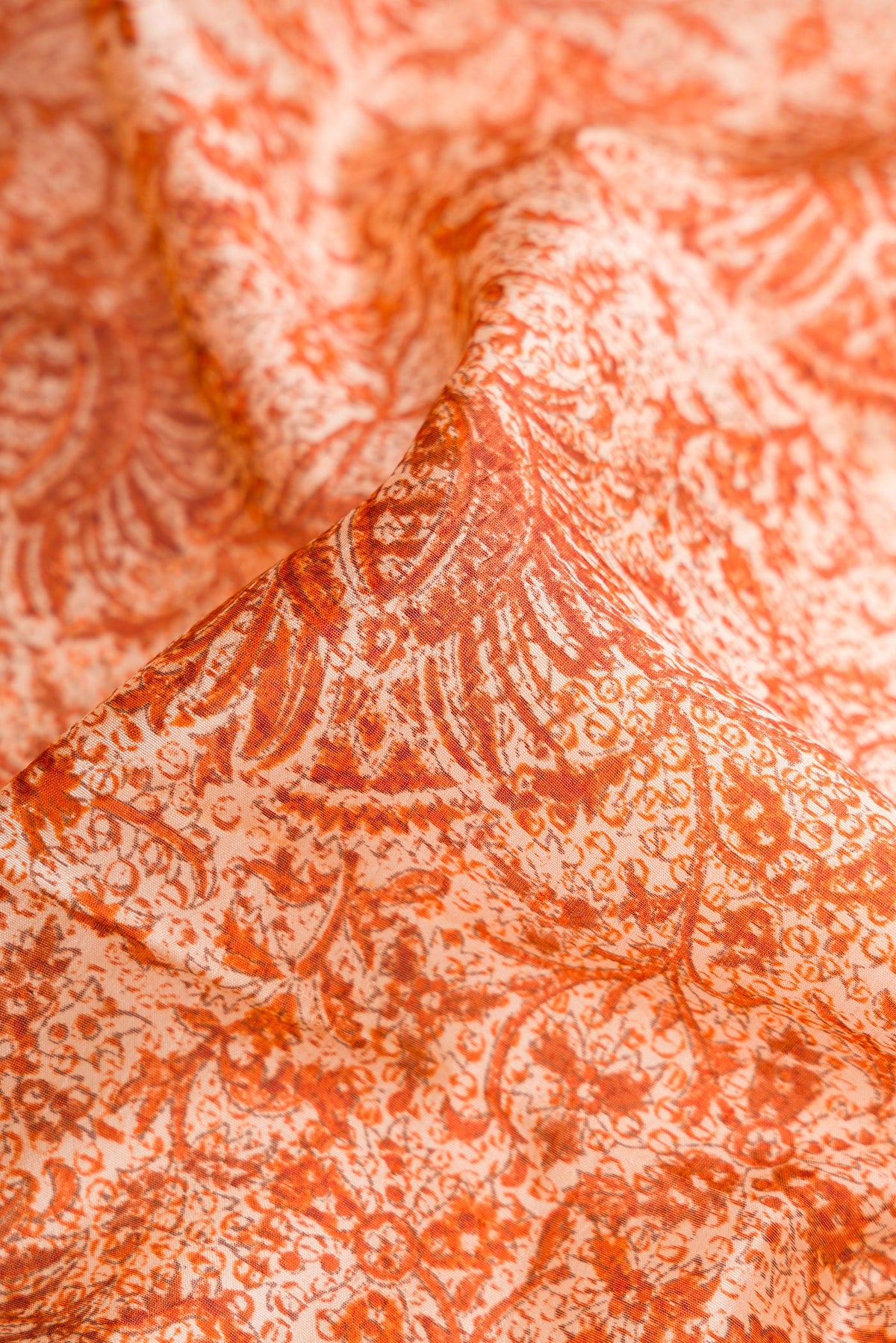 Close up of Orange Dual Tone Tussar Silk Saree with Printed design on the body and Printed Border.  displaying folds