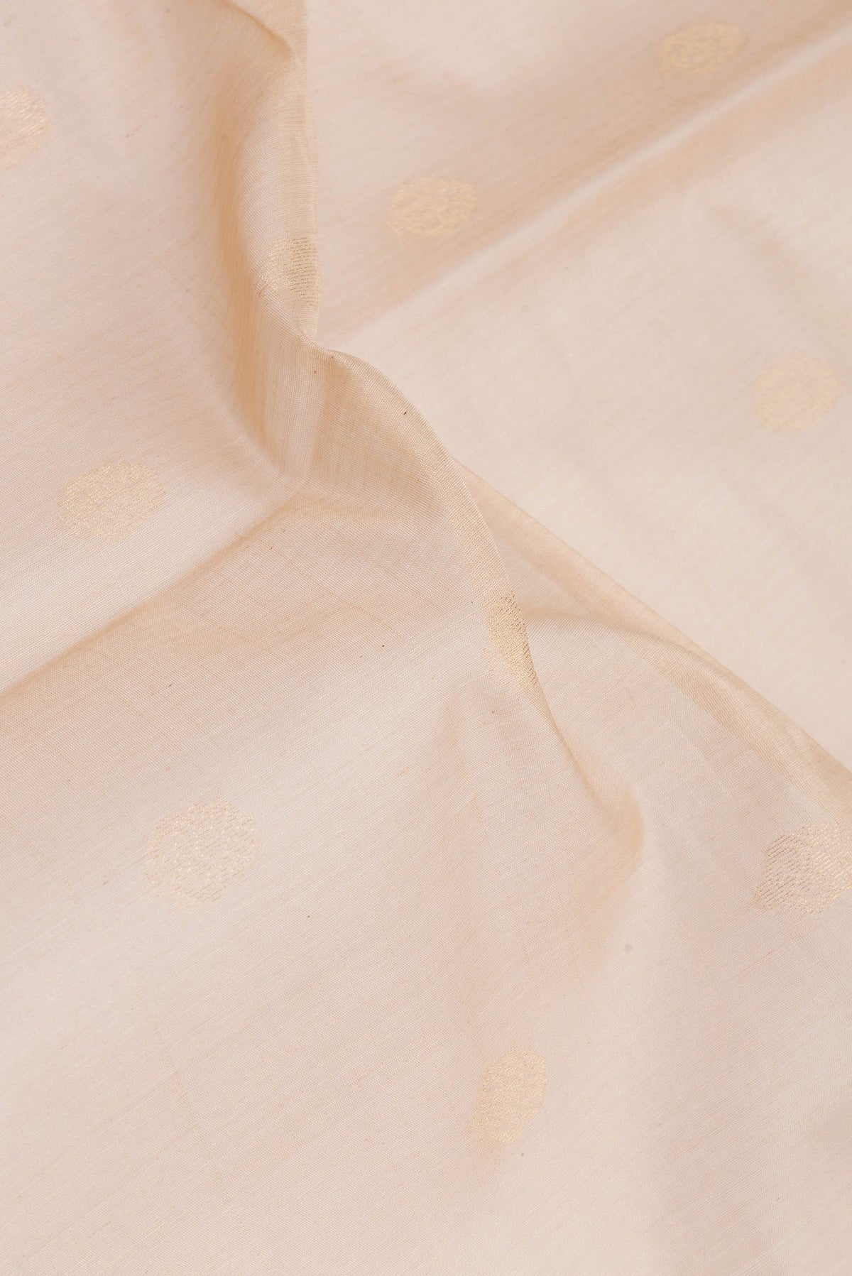 Close up of Beige Silk Cotton Saree with Zari Butta on the body and Zari Border.  displaying folds