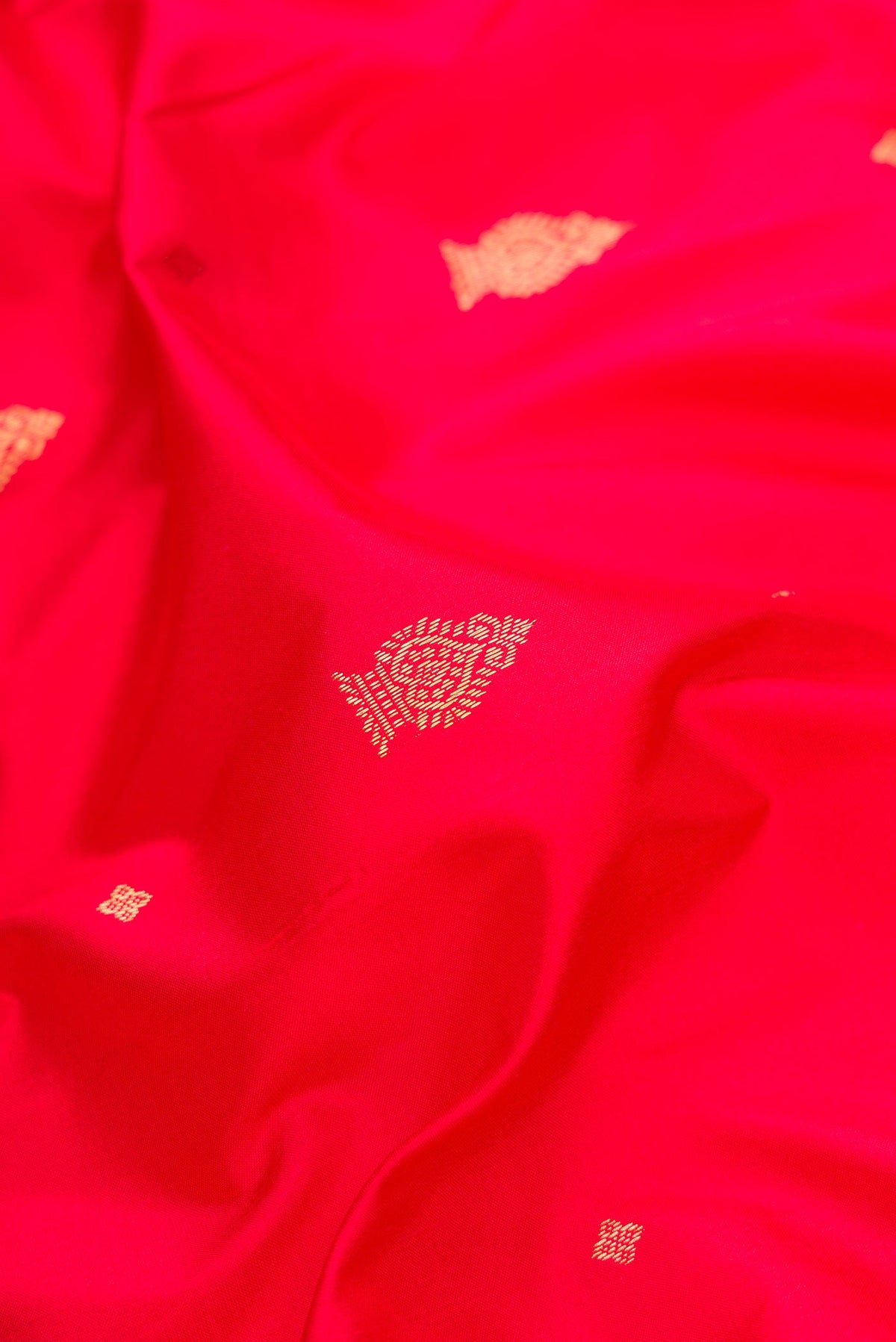 Close up of Red Dual Tone Kanchipuram Silk Saree with Zari Butta on the body and Temple Border.  displaying folds