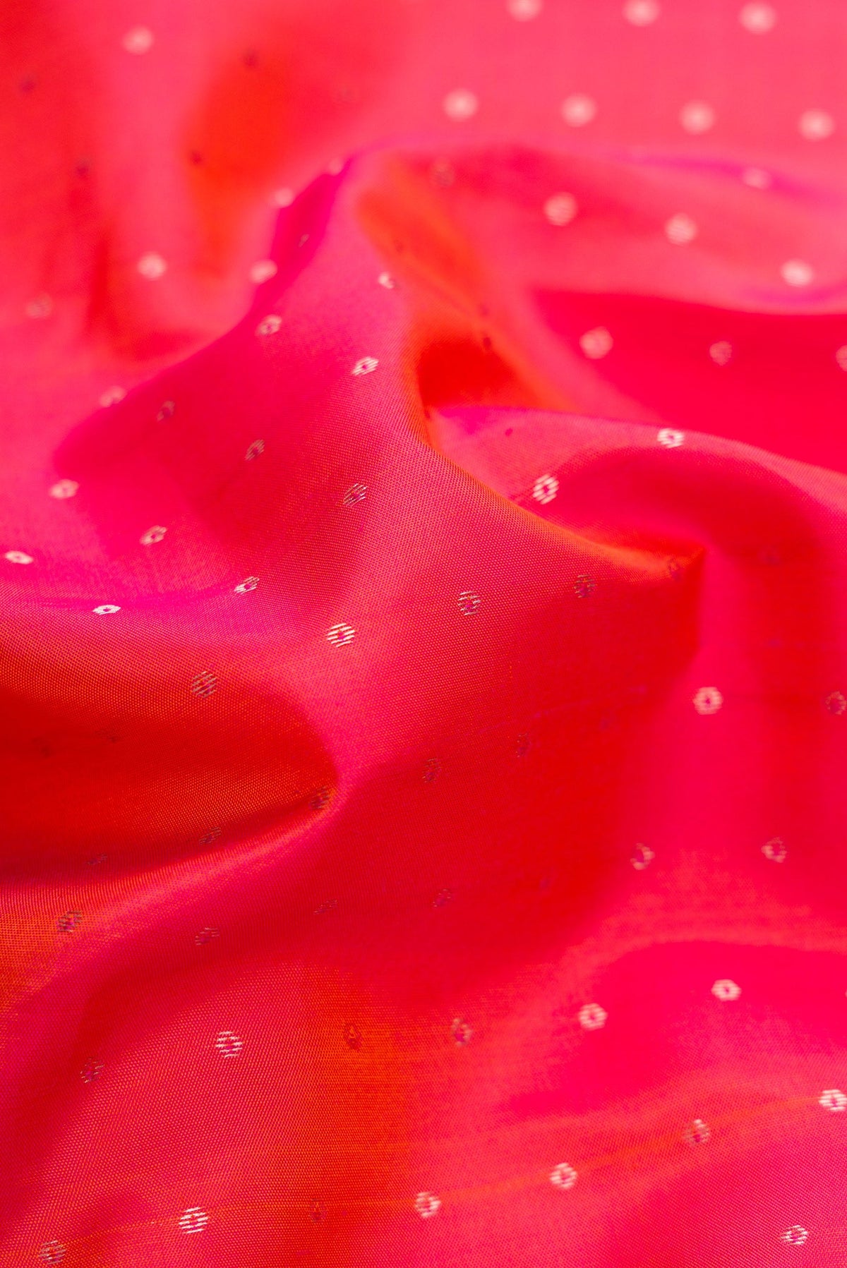 Close up of Coral Dual Tone Kanchipuram Silk Saree with Zari Butta on the body and Zari Border.  displaying folds