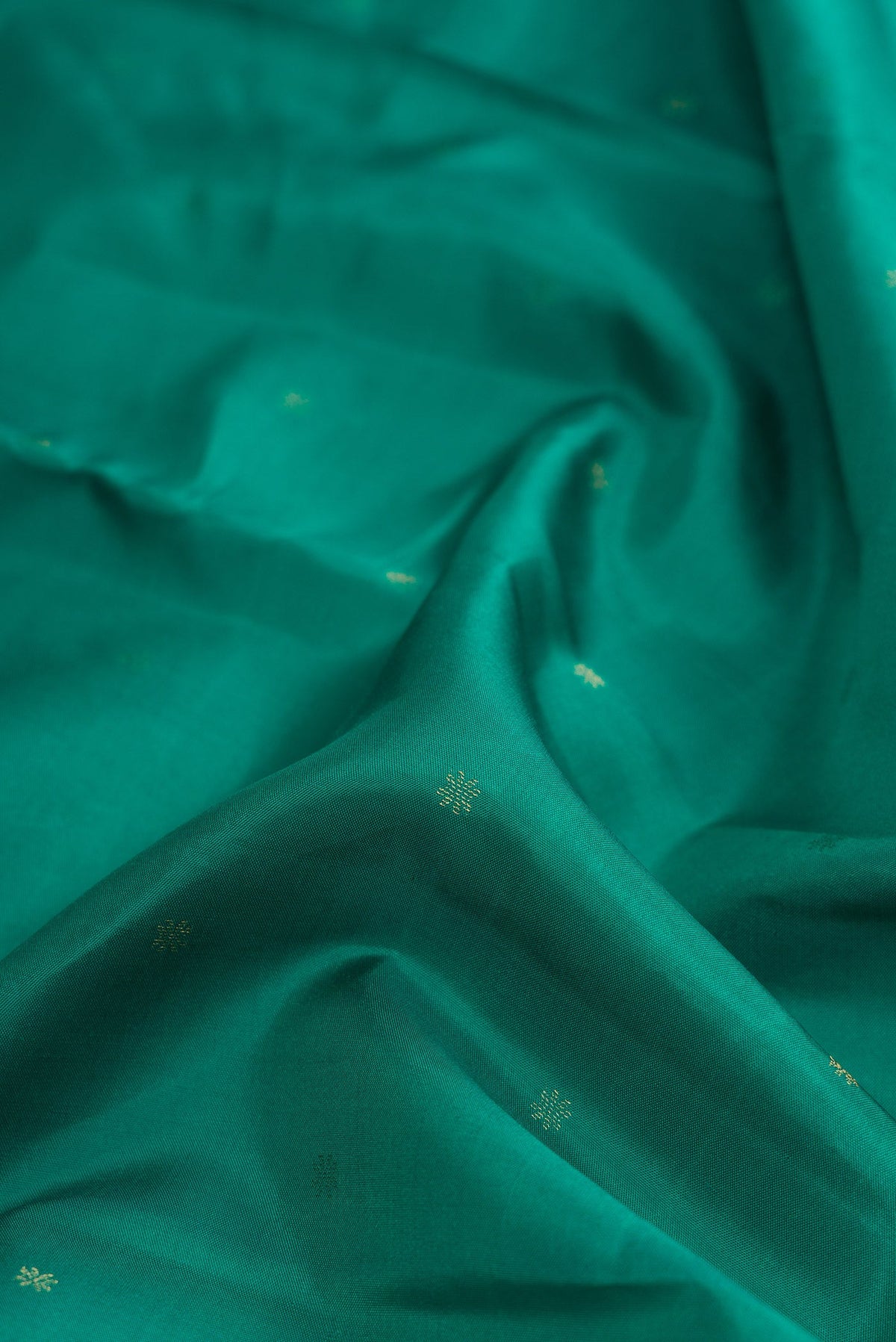 Close up of Green Dual Tone Kanchipuram Silk Saree with Zari Butta on the body and Zari Border.  displaying folds