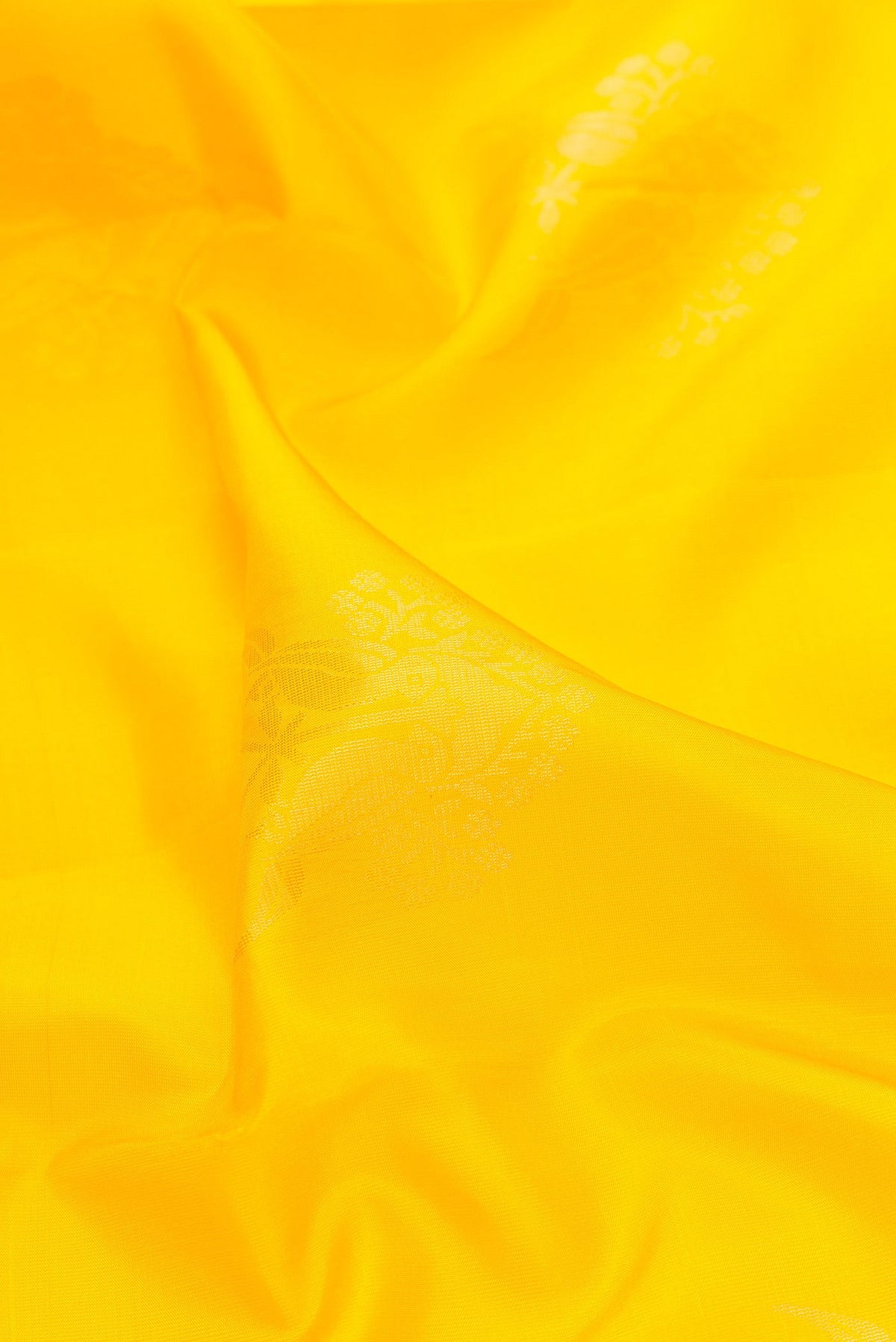 Close up of Yellow Dual Tone Soft Silk Saree with Zari Butta on the body and Zari Border.  displaying folds