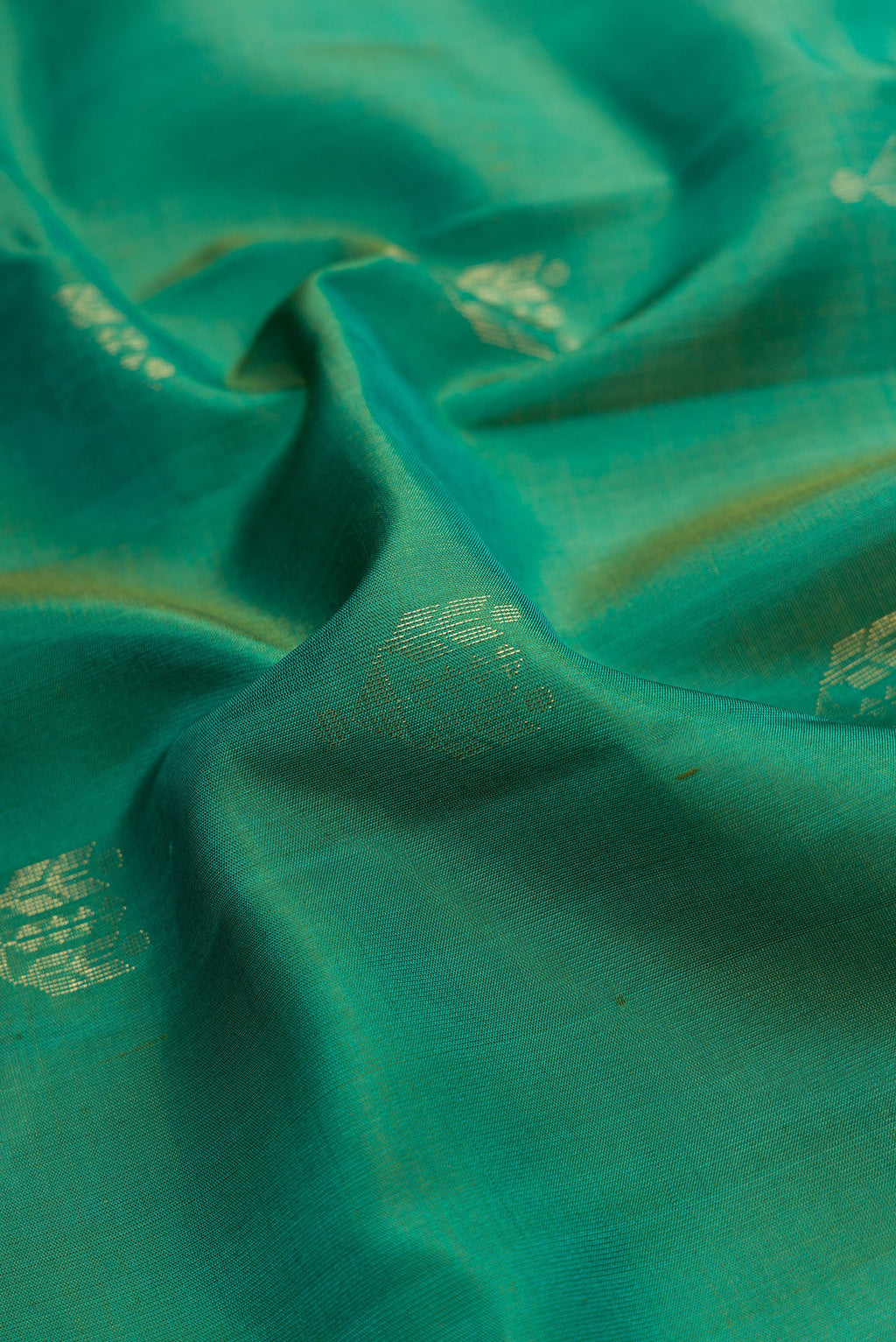 Close up of Green Dual Tone Soft Silk Saree with Zari Butta on the body and Zari Border.  displaying folds