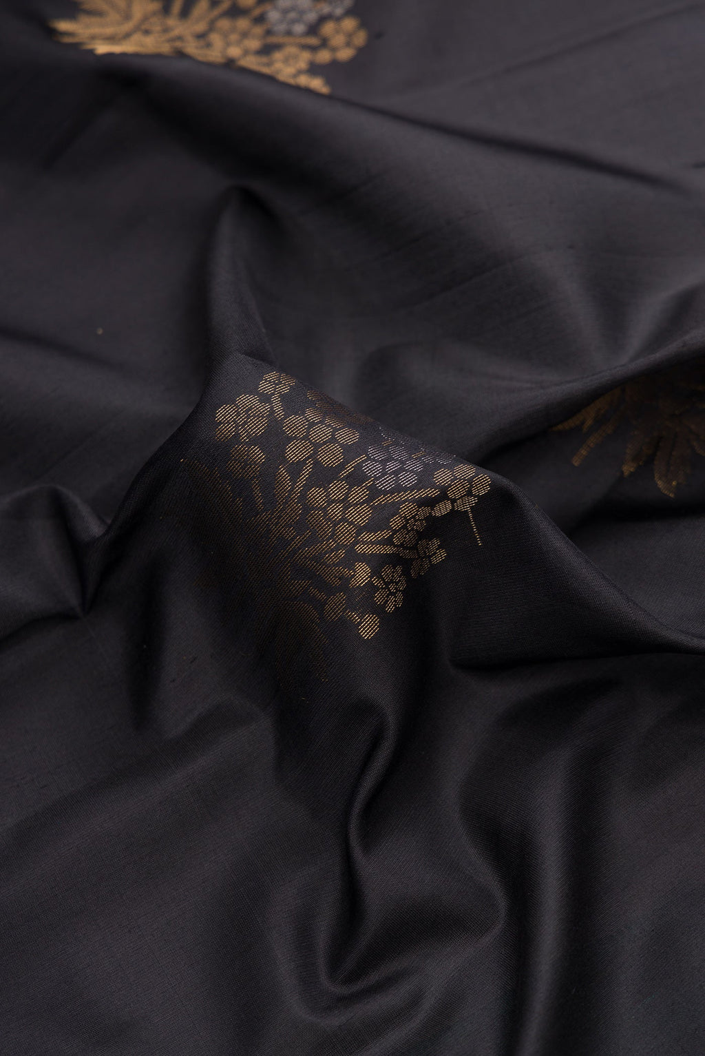 Close up of Black Dual Tone Soft Silk Saree with Zari Butta on the body and Zari Border.  displaying folds