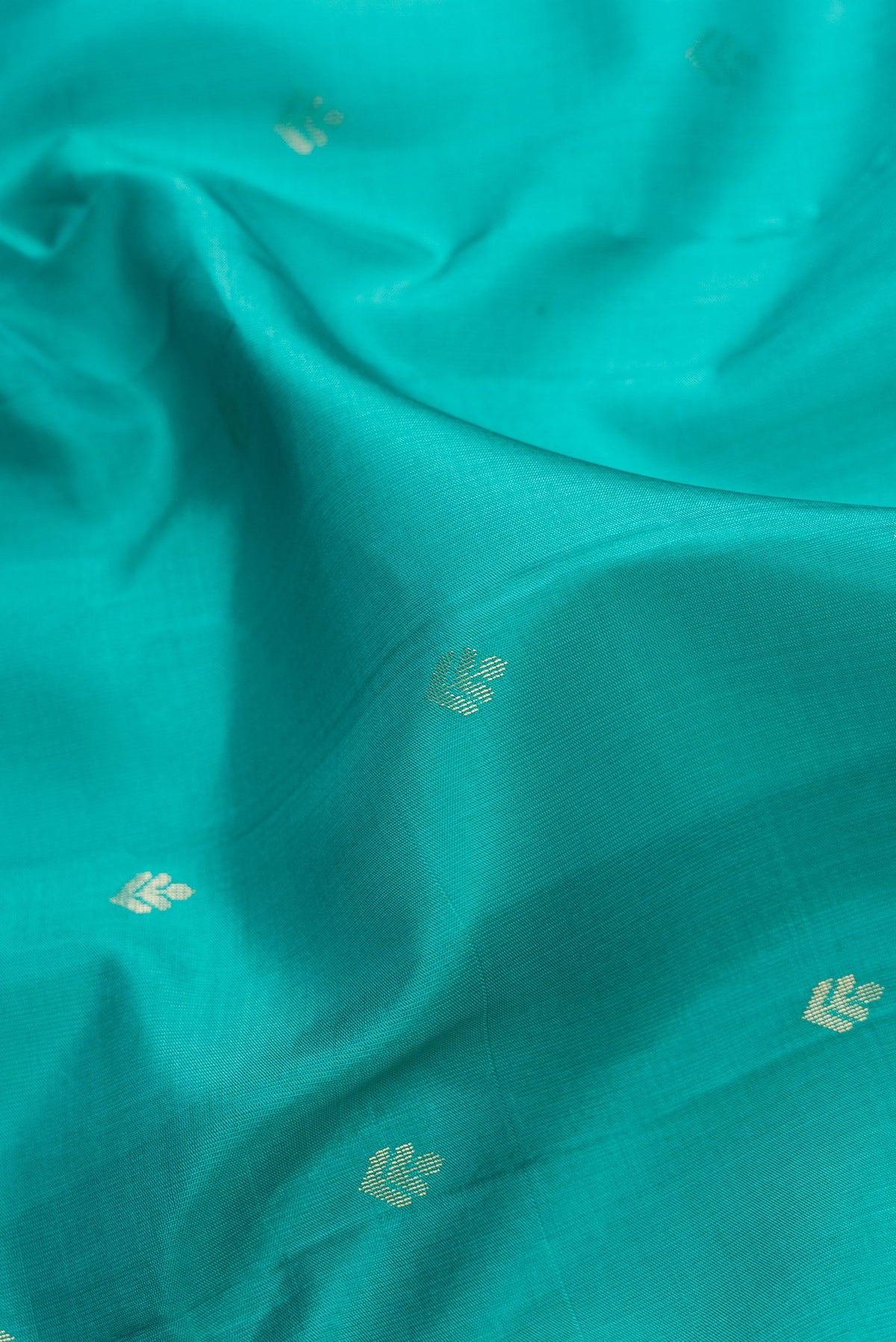 Close up of Green Dual Tone Soft Silk Saree with Zari Butta on the body and Zari Border.  displaying folds