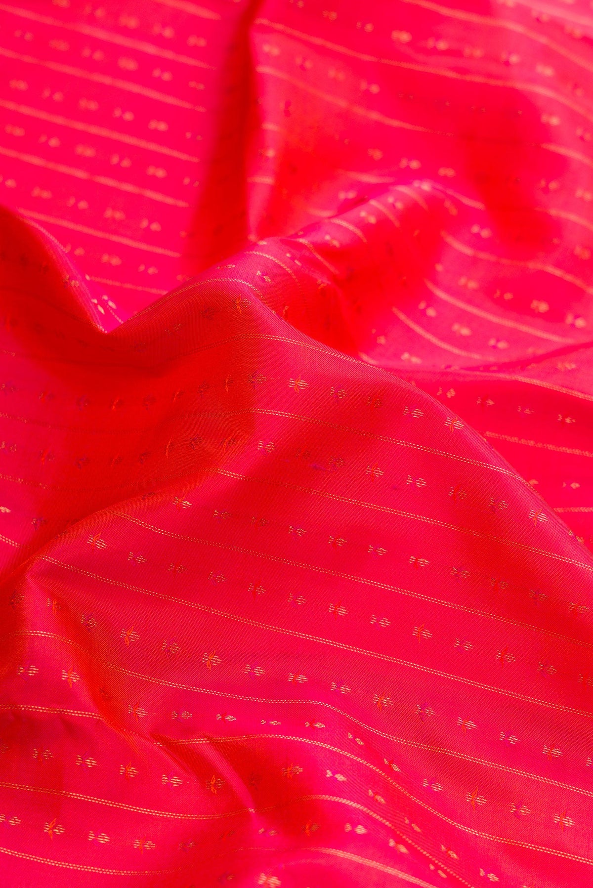 Close up of Orange Dual Tone Kanchipuram Silk Saree with Zari Butta on the body and Zari Border.  displaying folds