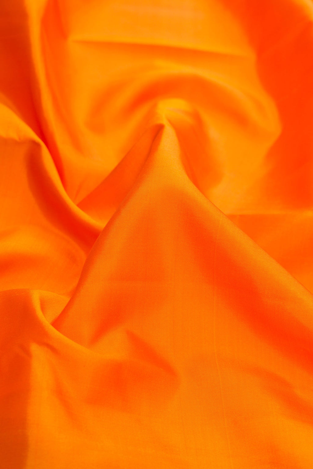 Close up of Orange Dual Tone Kanchipuram Silk Saree with Plain Body and Zari Border.  displaying folds