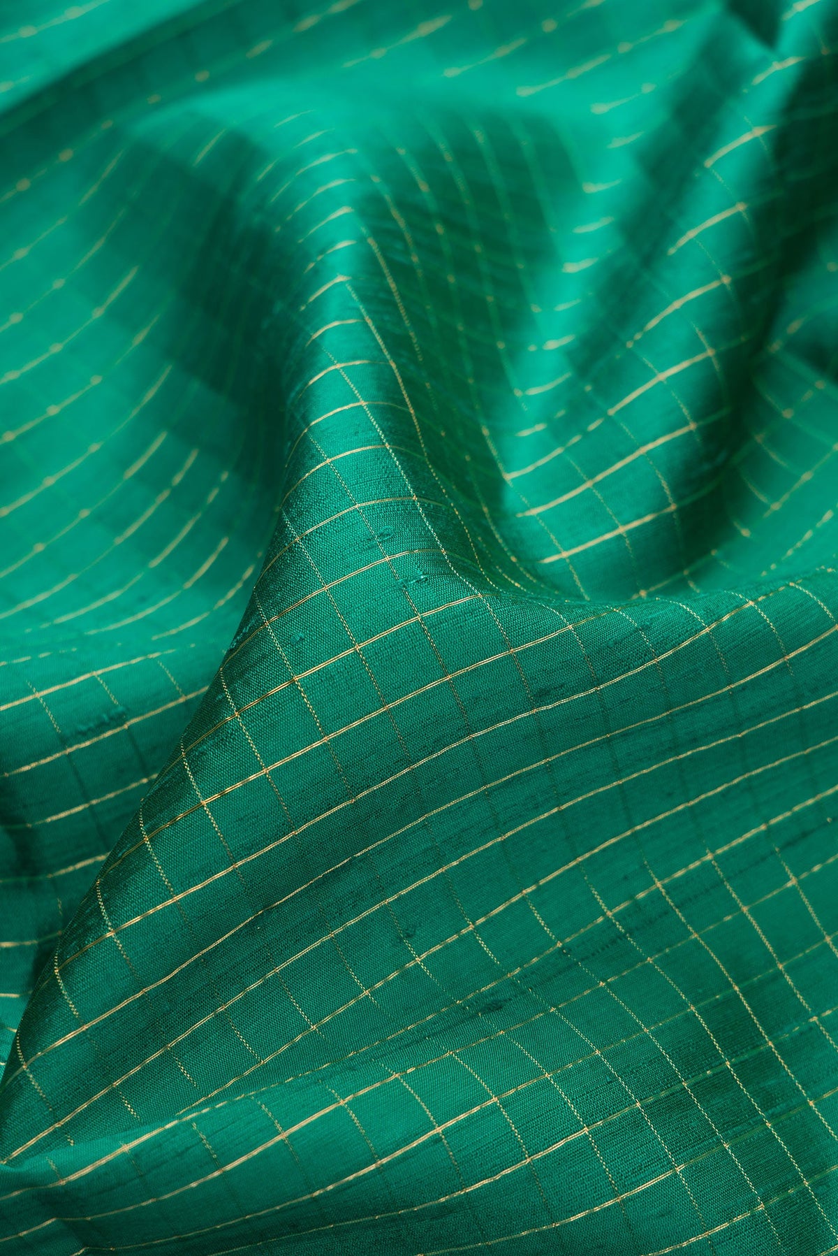 Close up of Green Dual Tone Raw Silk Saree with Checked design on the body and Thin Zari Line.  displaying folds