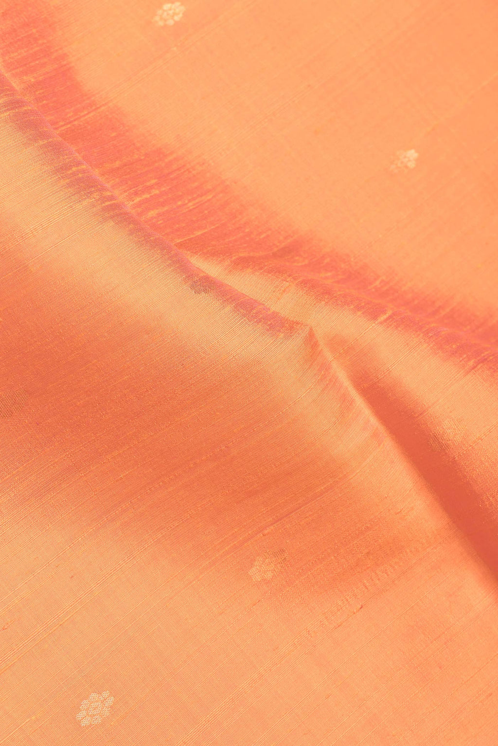 Close up of Orange Dual Tone Raw Silk Saree with Zari Butta on the body and Zari Border.  displaying folds