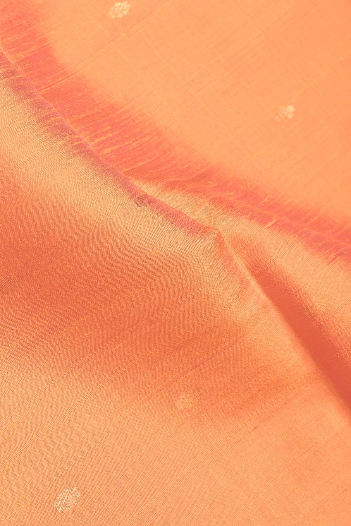Close up of Orange Dual Tone Raw Silk Saree with Zari Butta on the body and Zari Border.  displaying folds