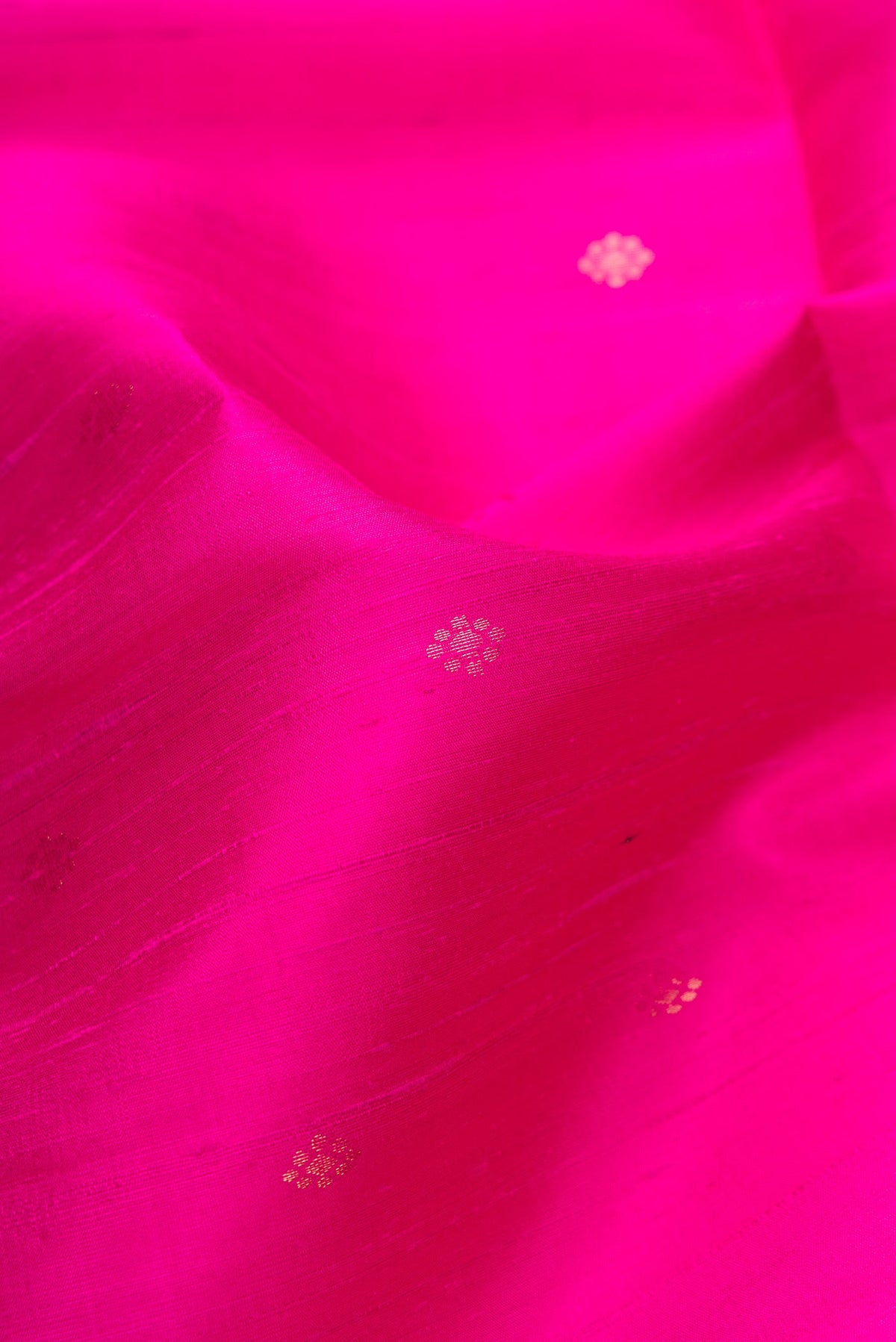 Close up of Magenta Dual Tone Raw Silk Saree with Zari Butta on the body and Zari Border.  displaying folds