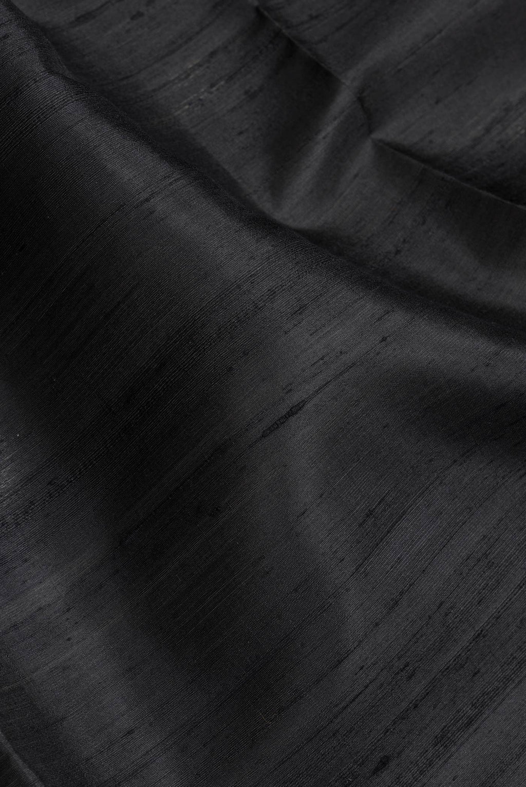 Close up of Black Dual Tone Raw Silk Saree with Plain Body and Zari Border.  displaying folds
