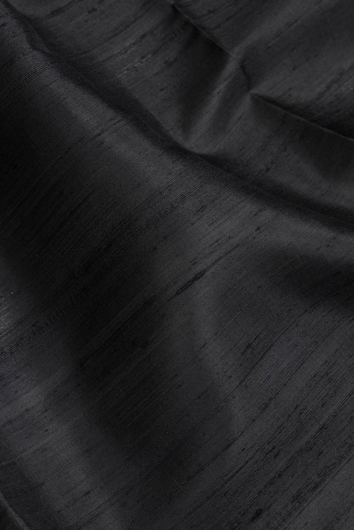Close up of Black Dual Tone Raw Silk Saree with Plain Body and Zari Border.  displaying folds