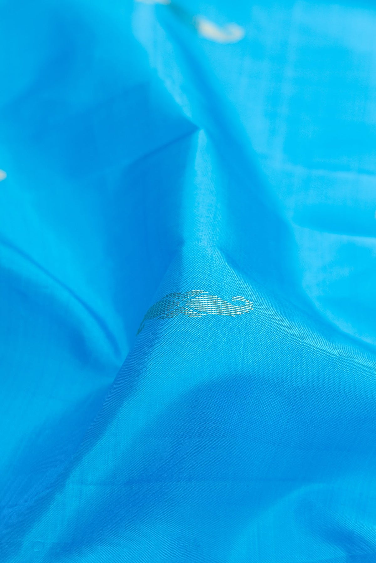 Close up of Sky Blue Kanchipuram Silk Saree with Zari Butta on the body and Fancy Border.  displaying folds