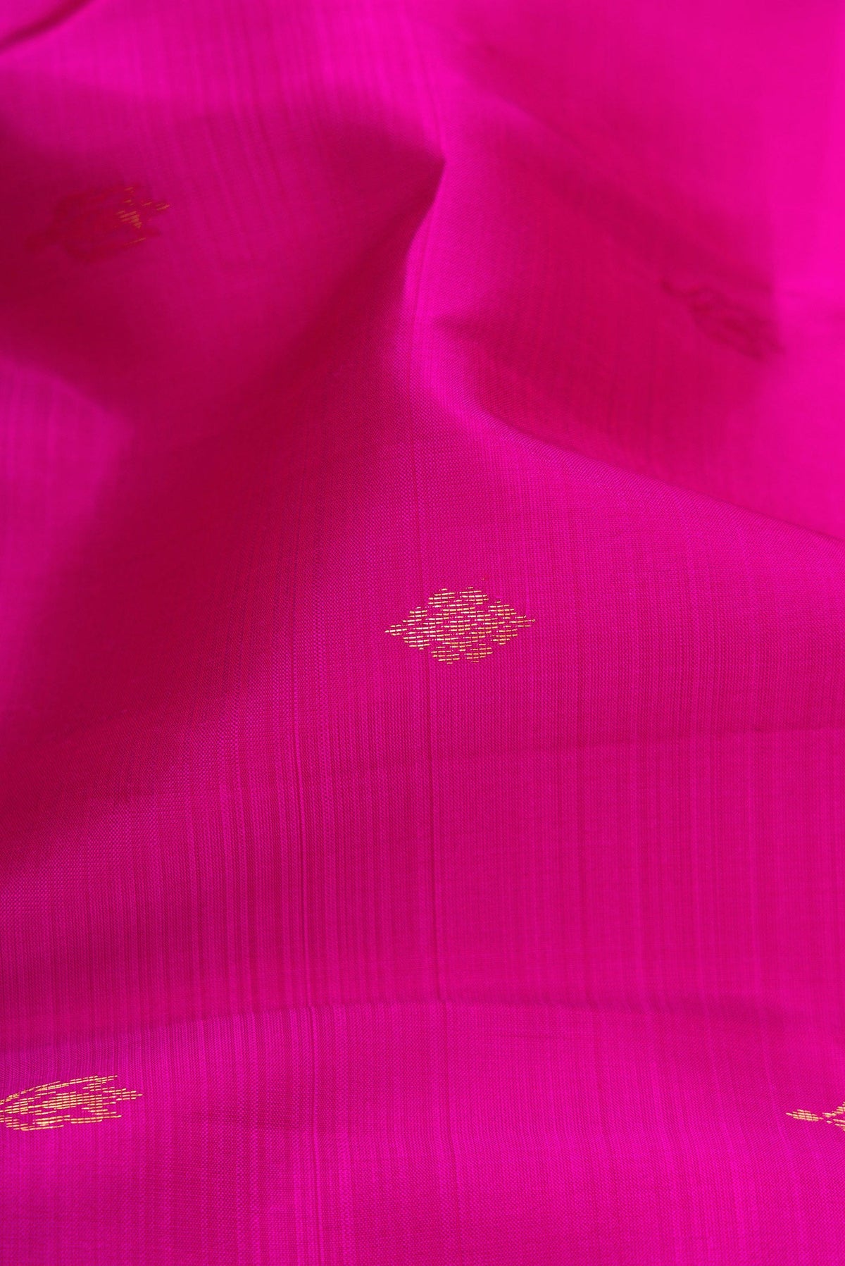 Close up of Magenta Kanchipuram Silk Saree with Zari Butta on the body and Zari Border.  displaying folds