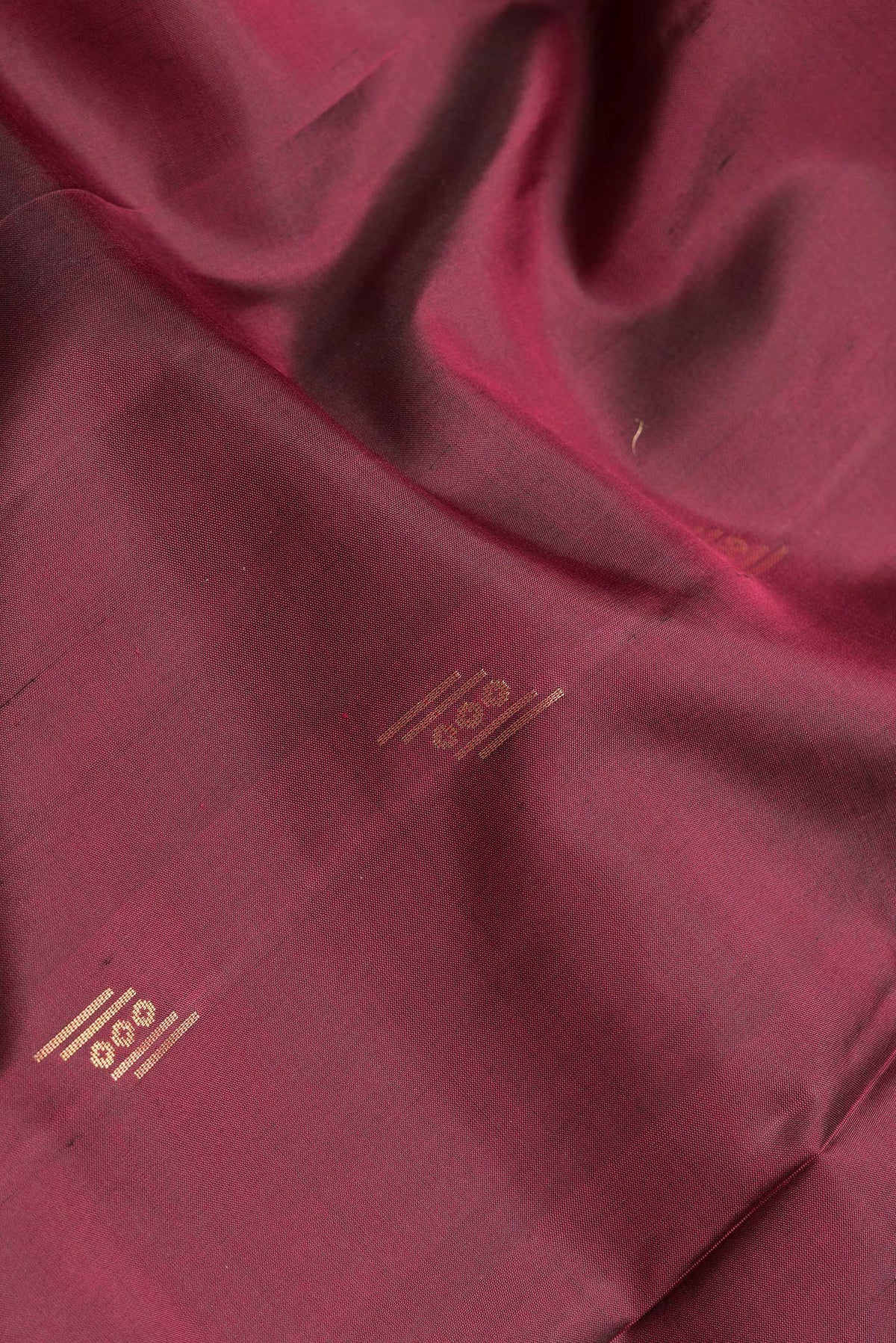 Close up of Maroon Dual Tone Soft Silk Saree with Zari Butta on the body and Zari Border.  displaying folds