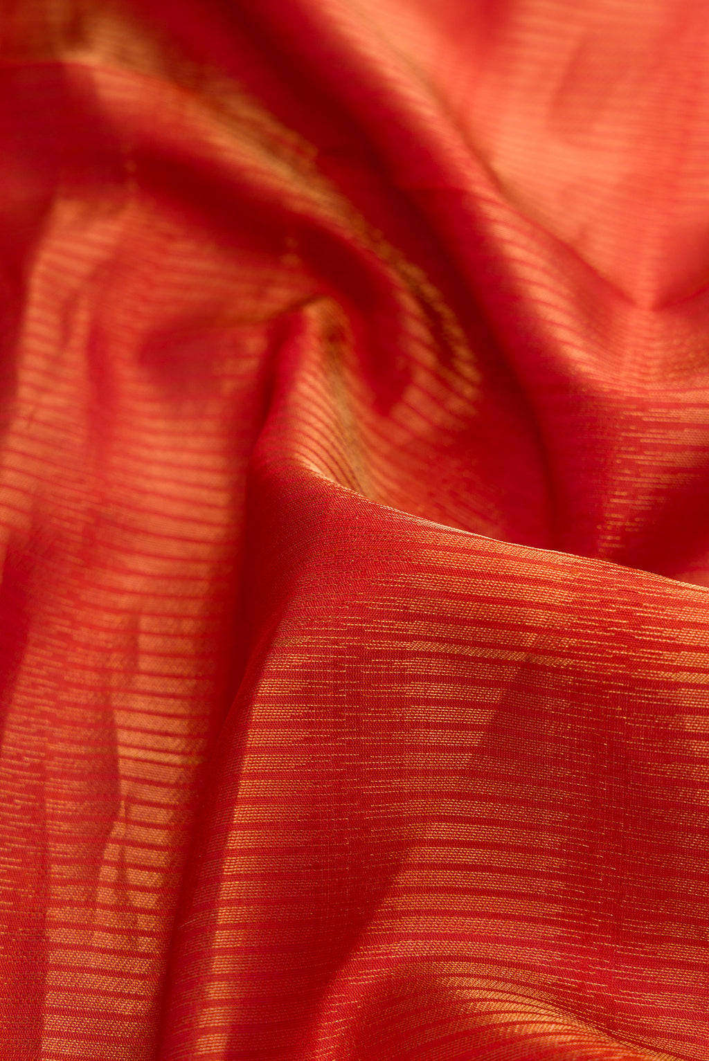Close up of Rust Soft Silk Saree with Zari Butta on the body and Zari Border.  displaying folds