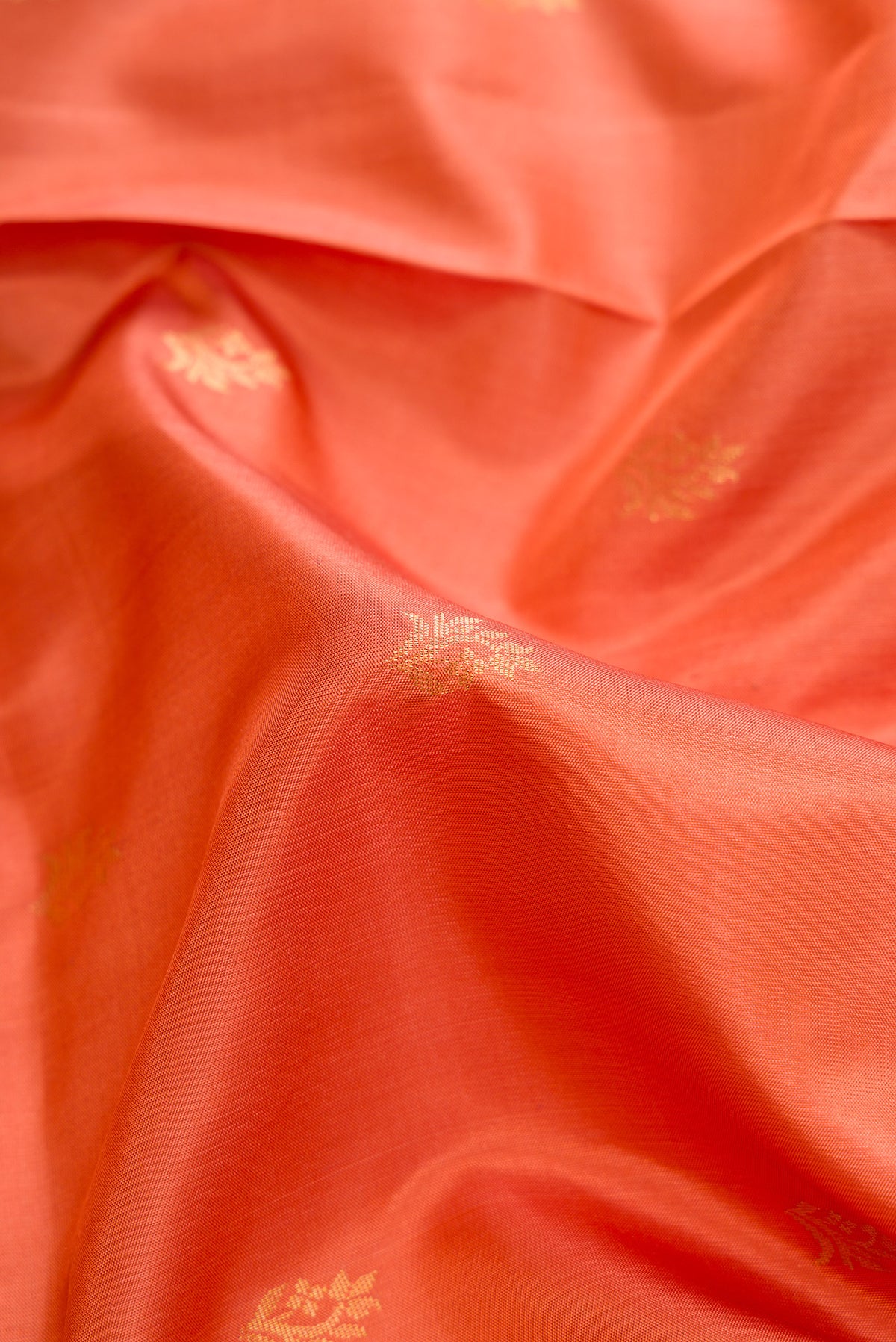 Close up of Peach Soft Silk Saree with Zari Butta on the body and Zari Border.  displaying folds